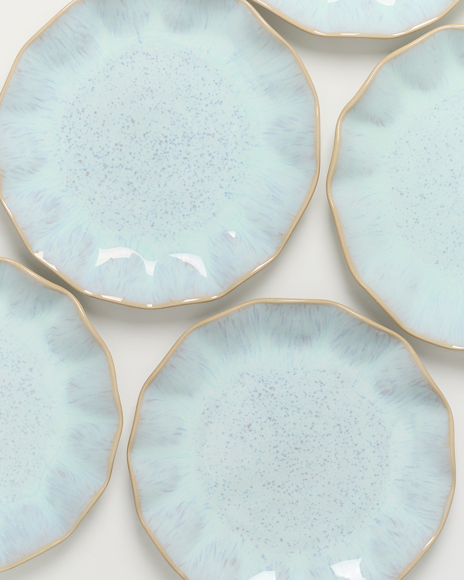 Fünf hellblaue, unregelmäßig geformte Teller mit goldenen Rändern und gesprenkelter Oberfläche.