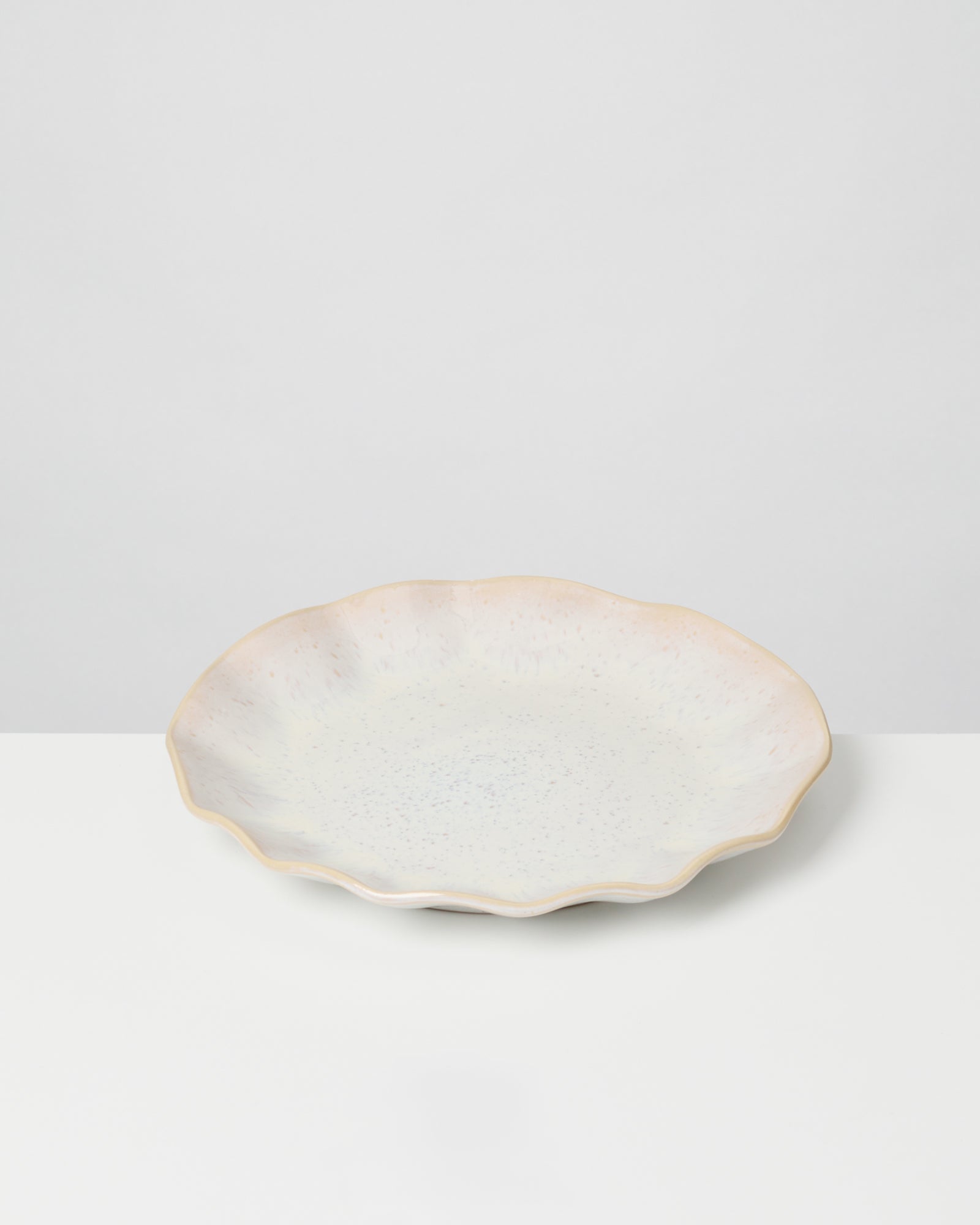 Weiße Keramikschale mit gewelltem Rand auf einem weißen Hintergrund.