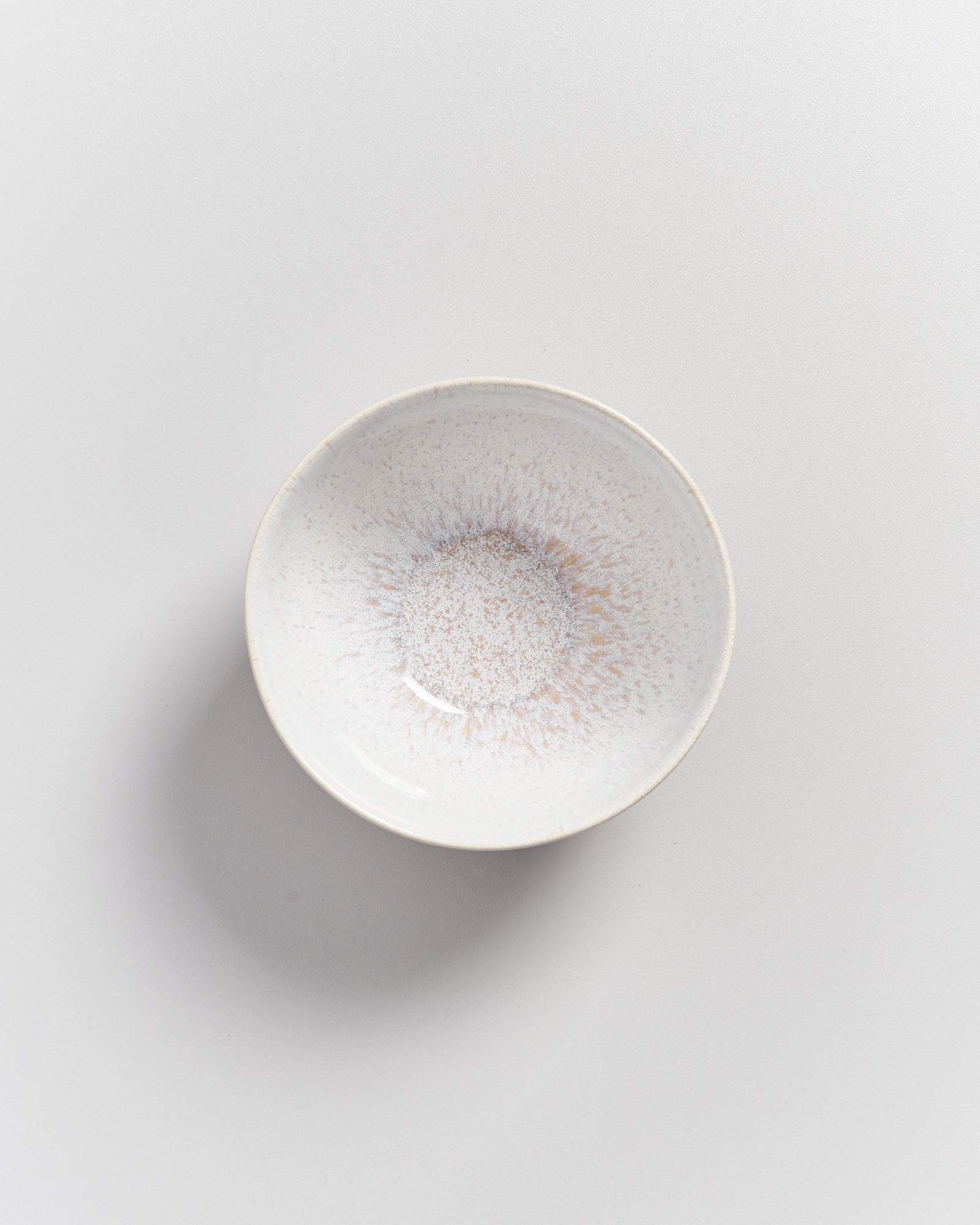 Keramikschale mit hellem, gesprenkeltem Design auf weißem Hintergrund.