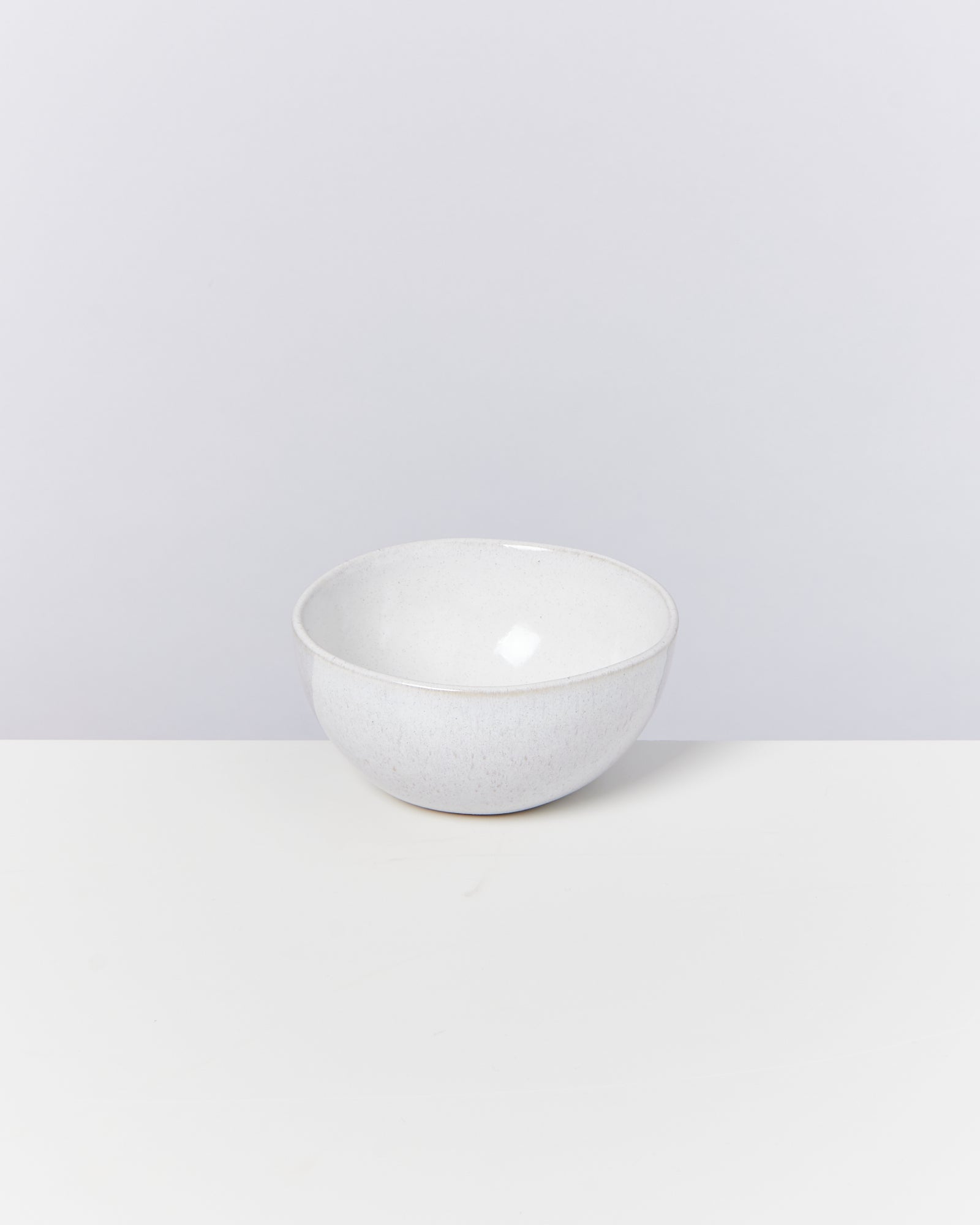 Weiße Keramikschale auf einem weißen Tisch vor einem neutralen Hintergrund.