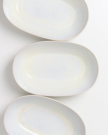 Drei weiß-beige ovale Teller sind auf einem weißen Hintergrund angeordnet.