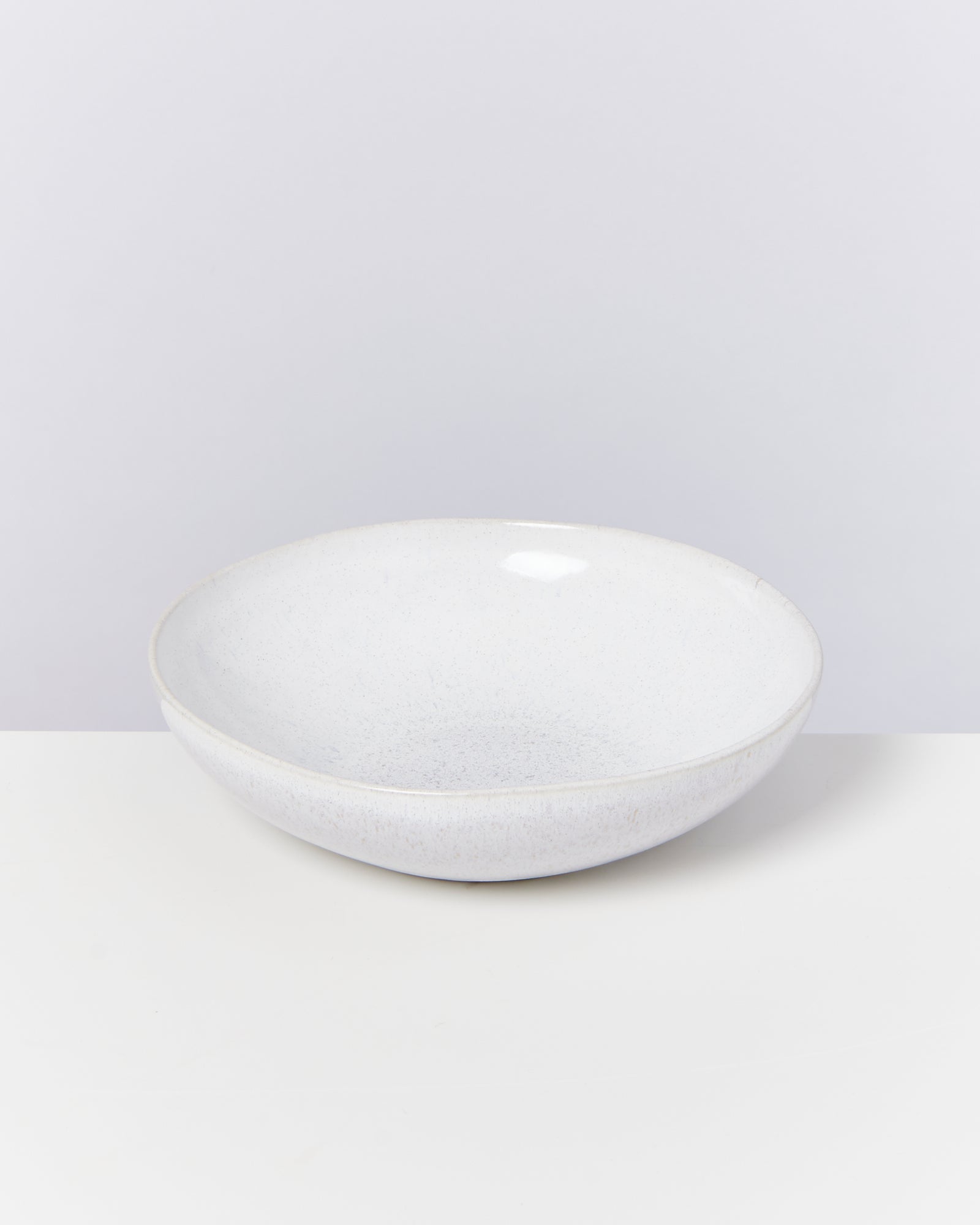 Eine weiße, runde Schüssel auf einem weißen Tisch vor einem hellgrauen Hintergrund.