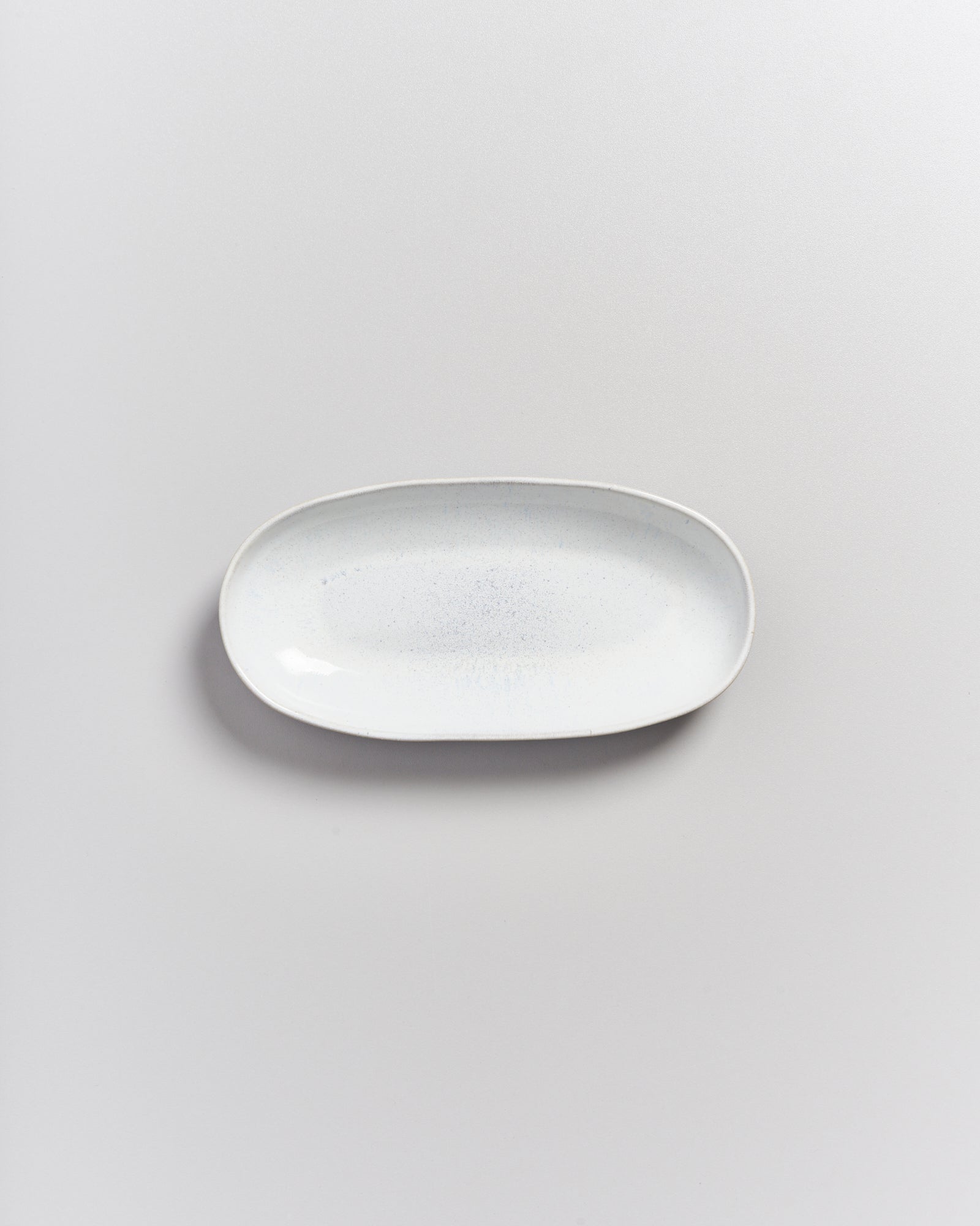 Weiße, längliche Keramikplatte auf einem hellgrauen Hintergrund.