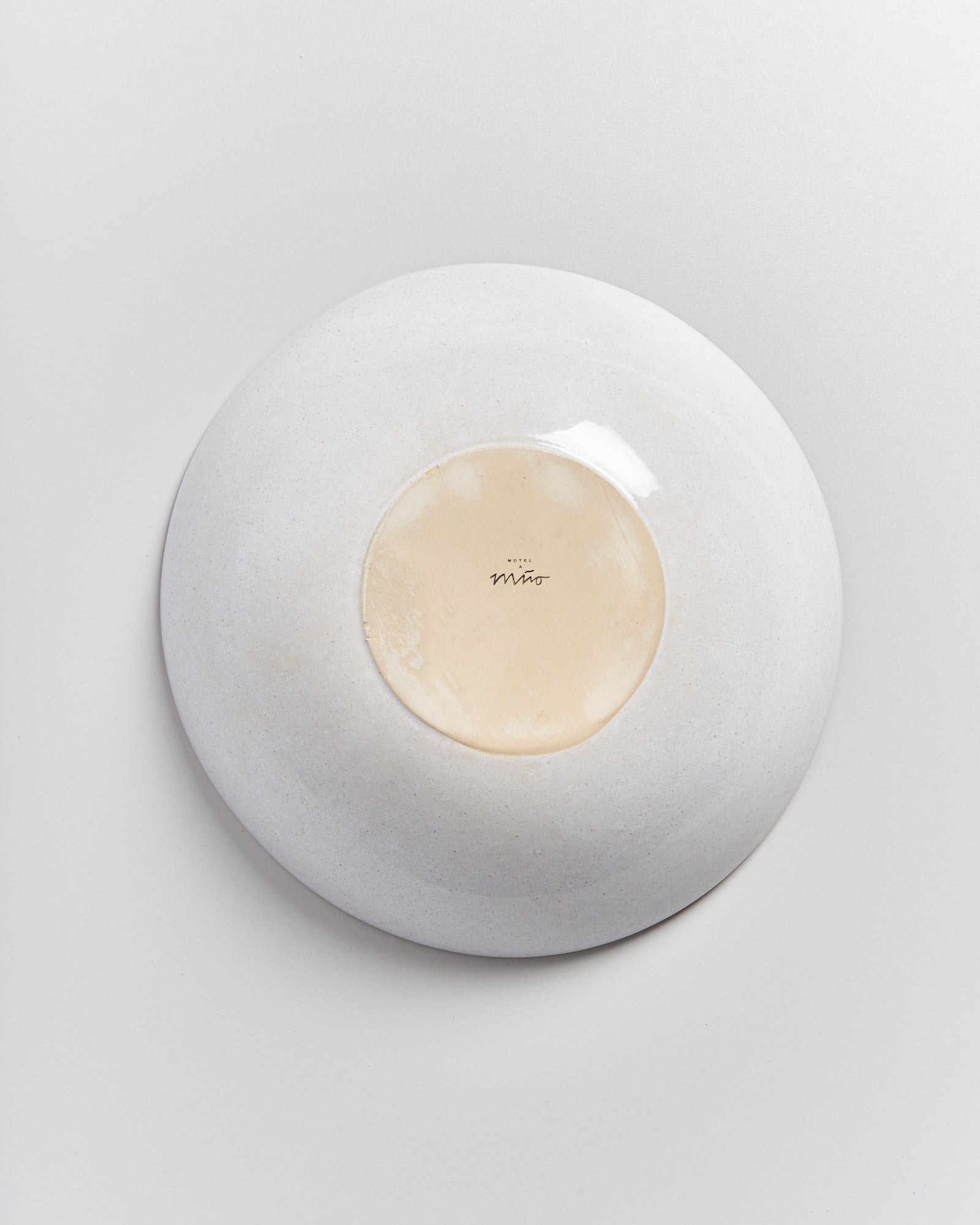 Weiße, umgedrehte Schale mit einem beigefarbenen Zentrum auf einem hellen Hintergrund.