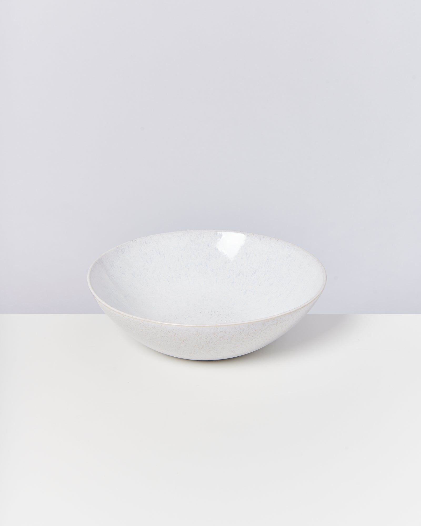 Weiße Keramikschale auf einem weißen Tisch vor einem hellgrauen Hintergrund.