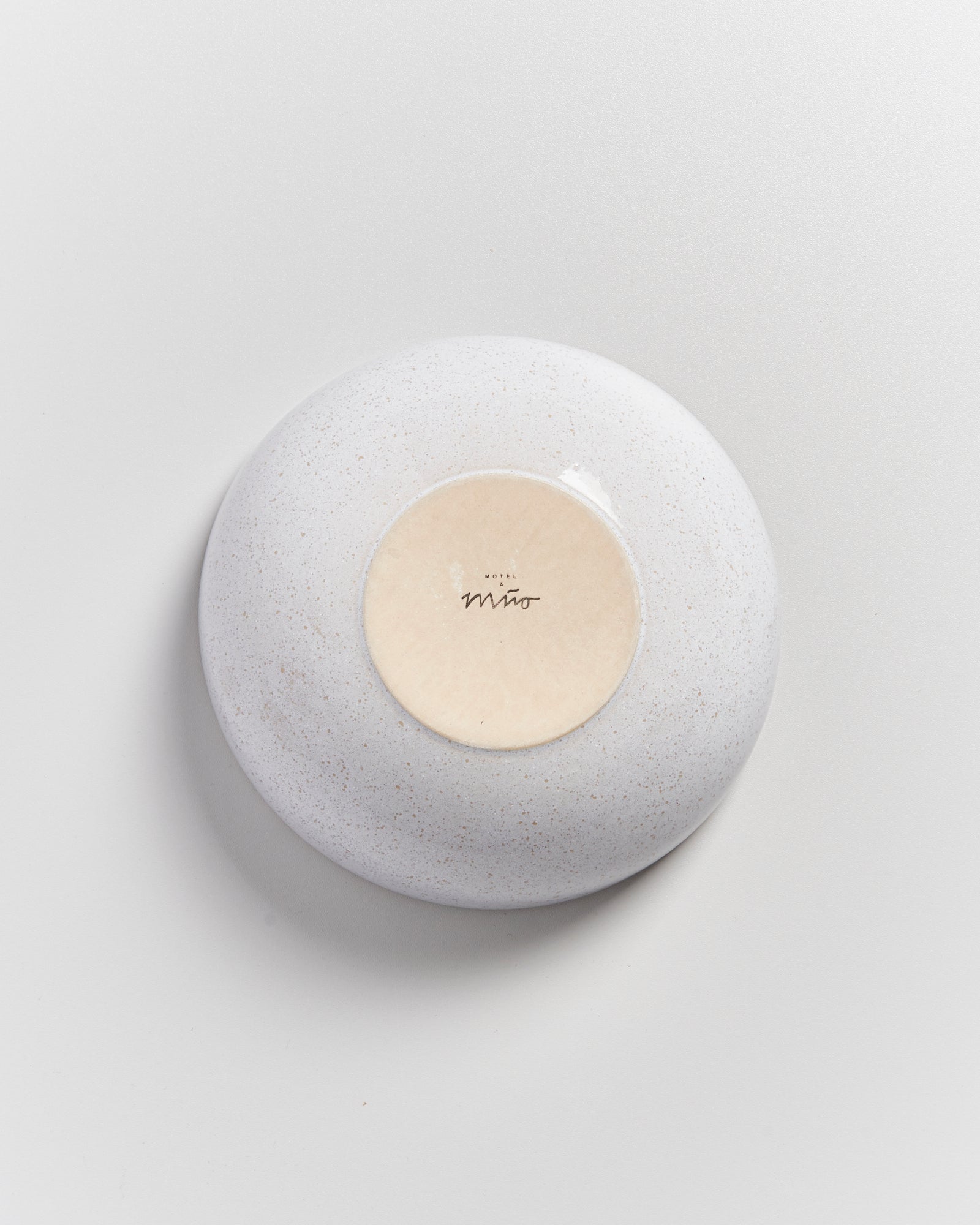 Weiße Keramikschale von oben, auf einem hellen Hintergrund, mit einem runden Aufkleber in der Mitte.