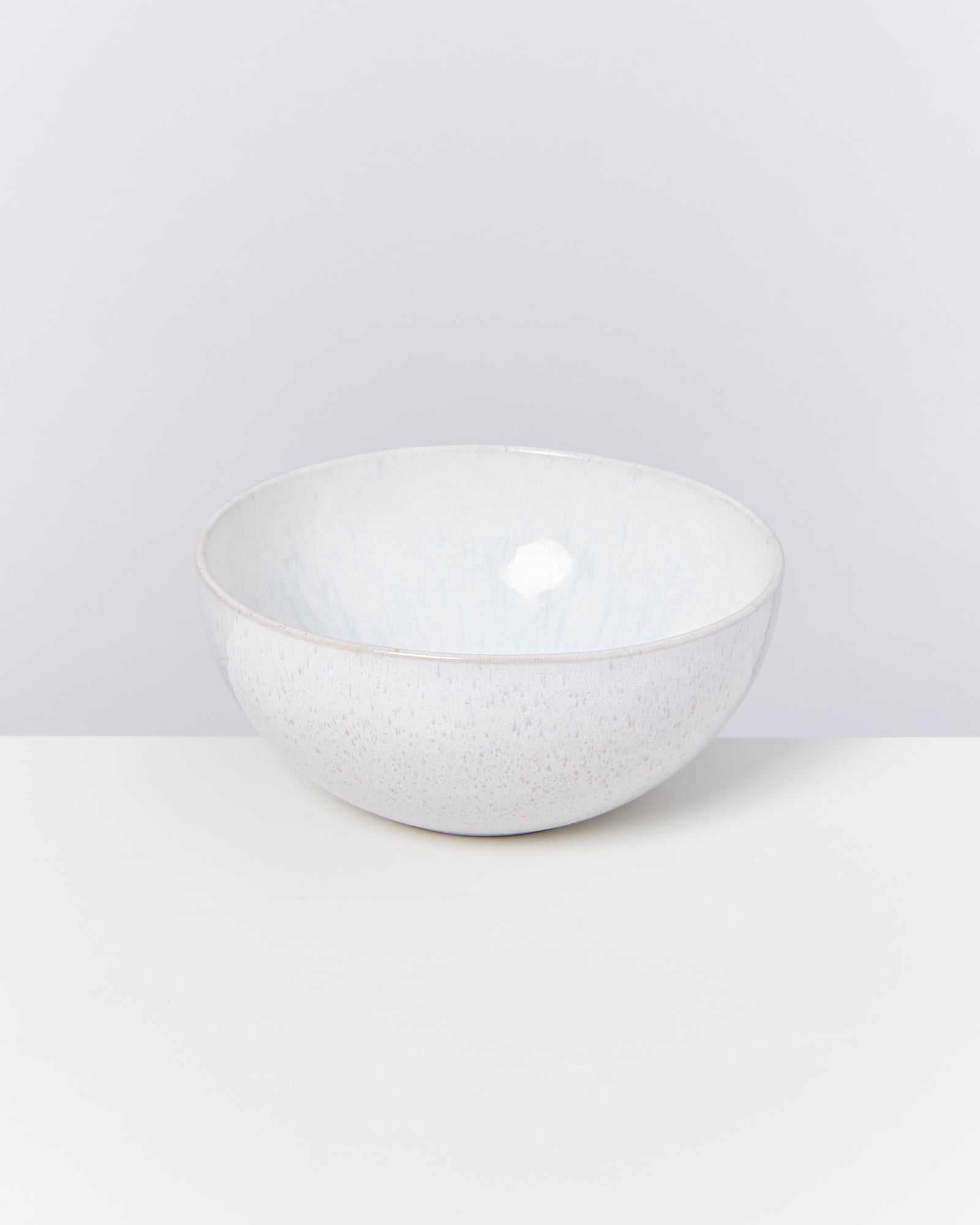Weiße Keramikschüssel mit dezentem Muster, auf weißem Hintergrund positioniert.