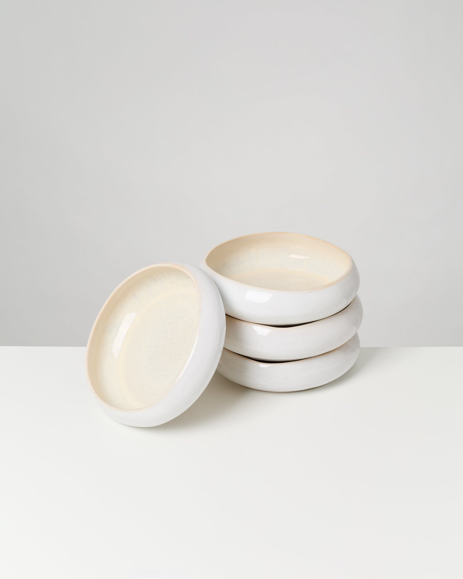 Ein Stapel weißer, runder Keramikschalen auf weißem Hintergrund.