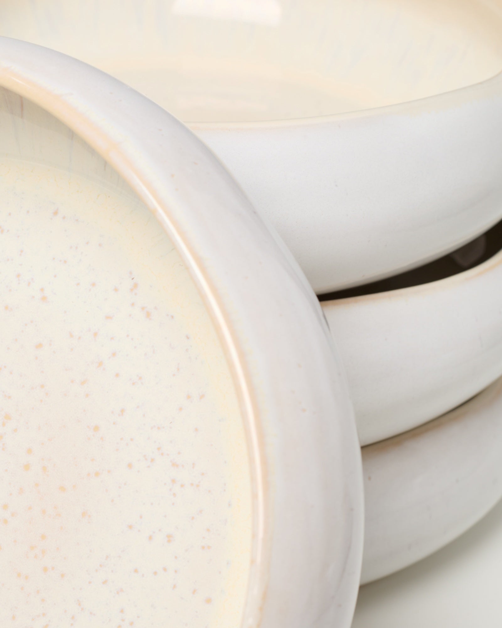 Nahaufnahme von gestapelten weißen Keramiktellern mit dezenten Sprenkeln.