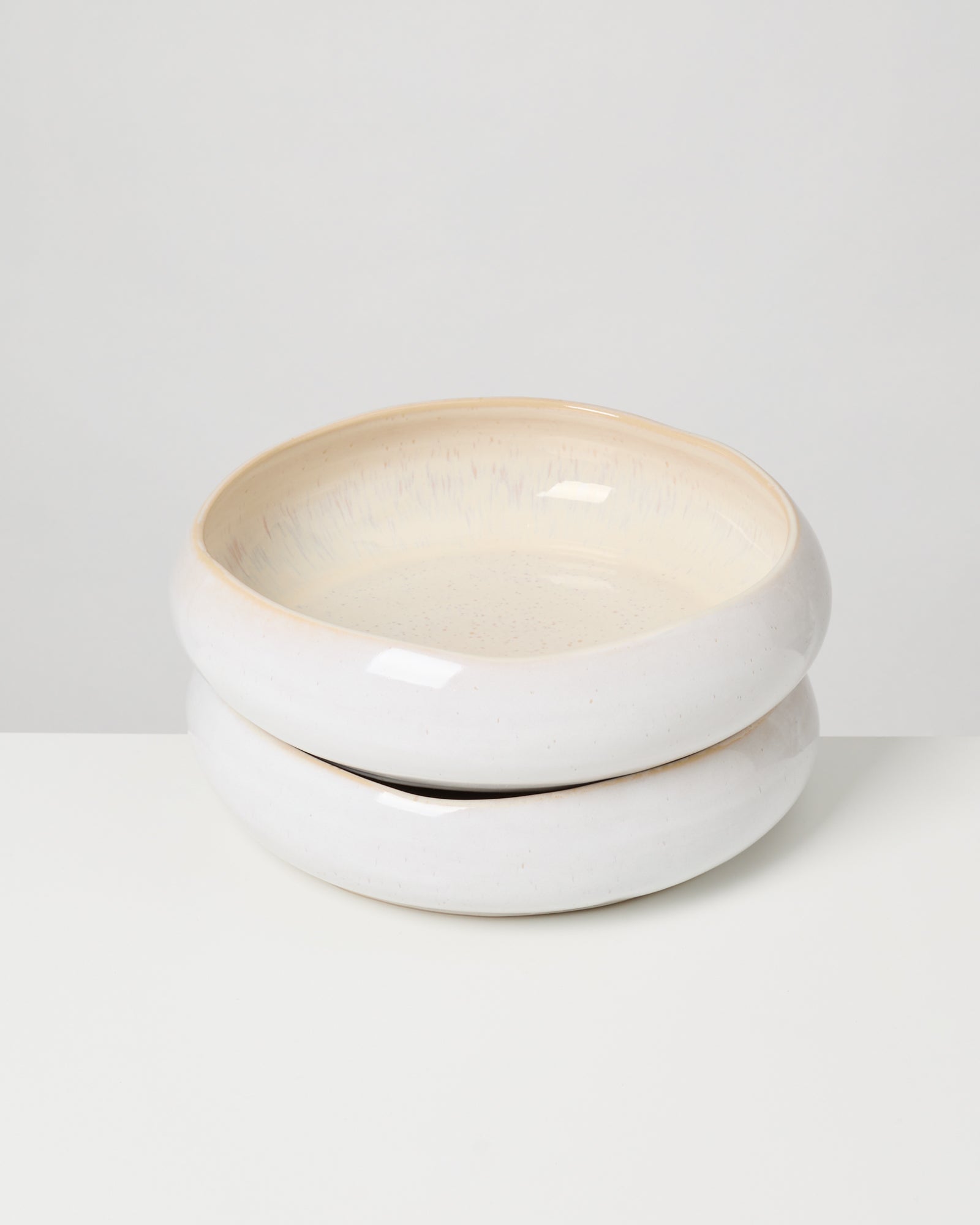 Zwei gestapelte, cremefarbene Keramikschalen auf weißem Hintergrund.
