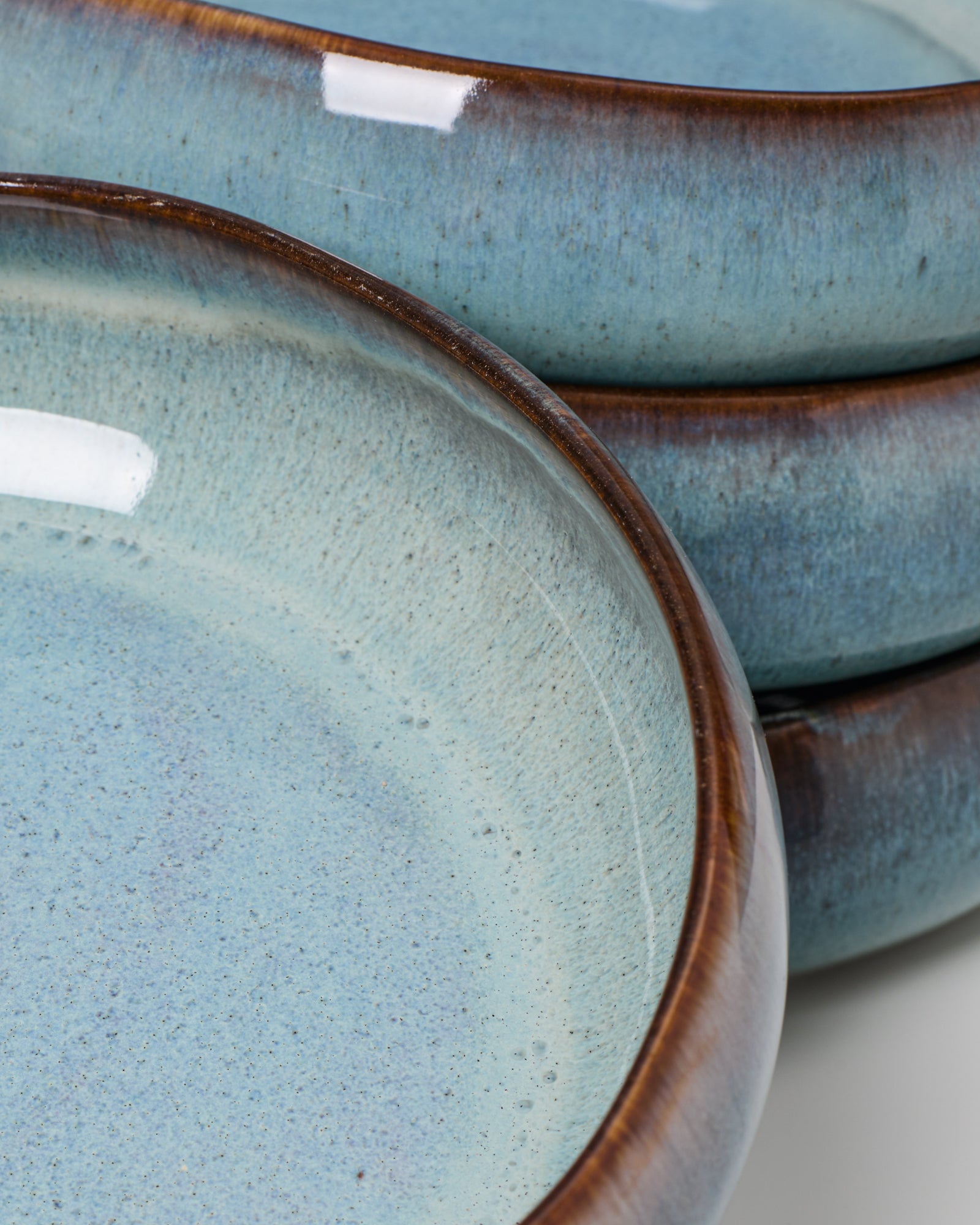 Nahaufnahme von drei gestapelten, blauen Keramiktellern mit dunklem Rand.