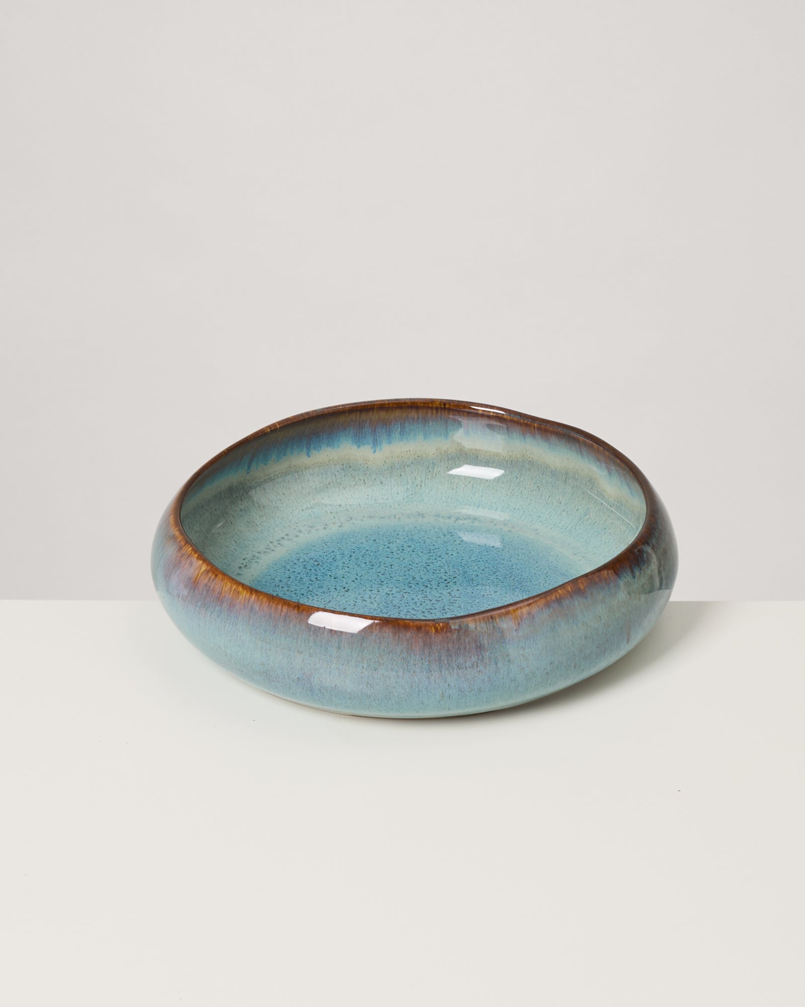 Keramikschale in Blau- und Brauntönen mit glänzender Glasur auf einem weißen Hintergrund.