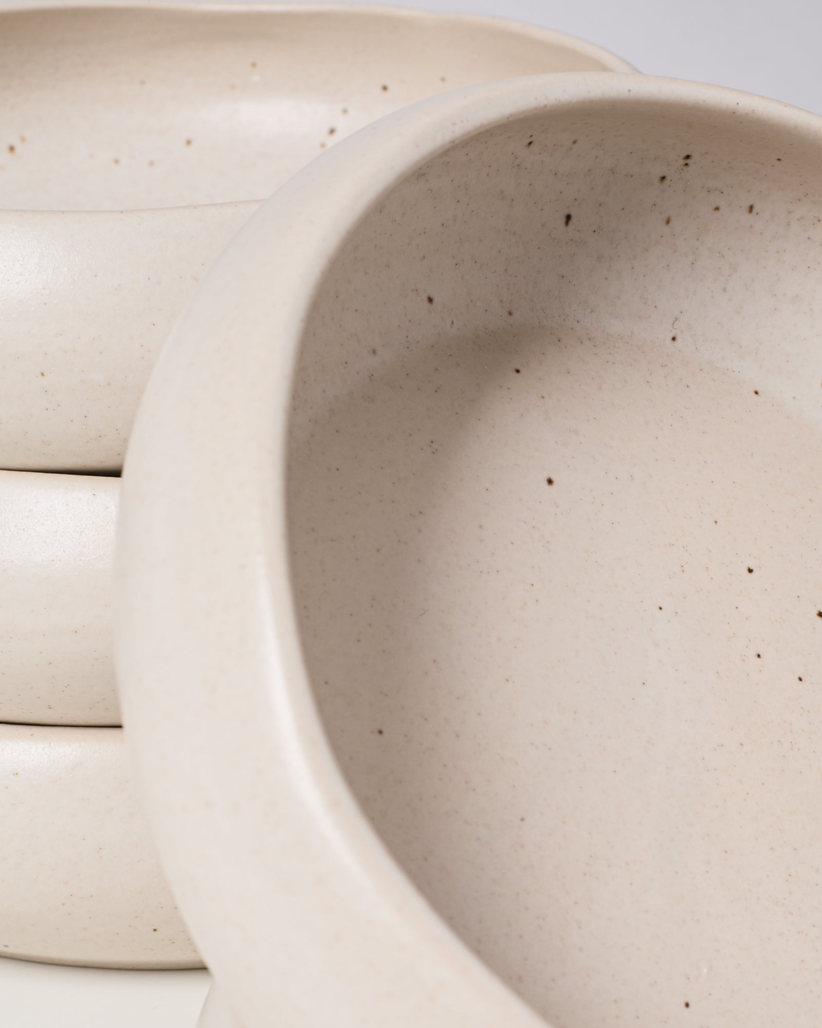 Nahaufnahme von stapelbaren weißen Keramikschalen mit kleinen dunklen Sprenkeln.