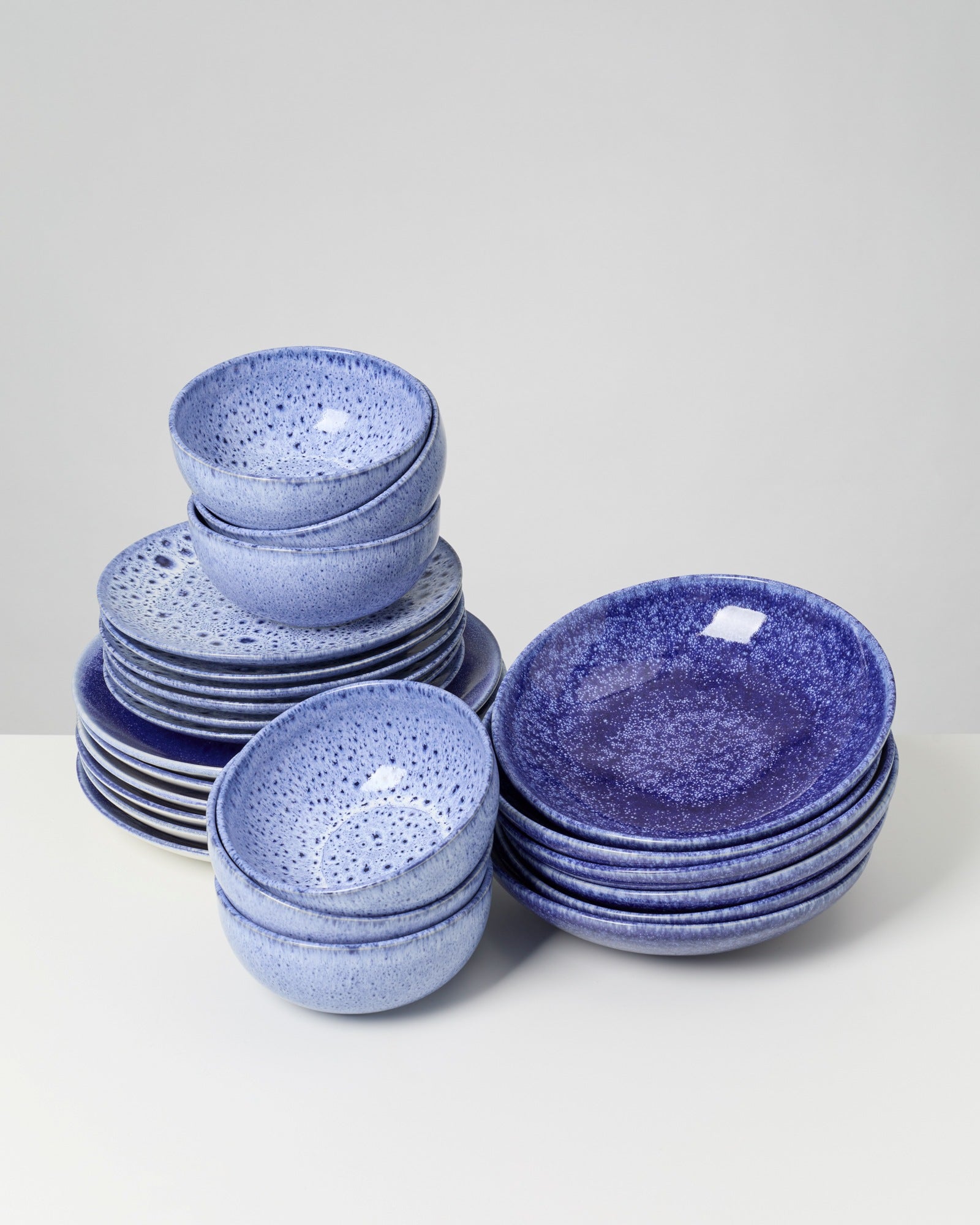 Stapel von blauen, geriffelten Schüsseln und Tellern auf einem weißen Tisch.