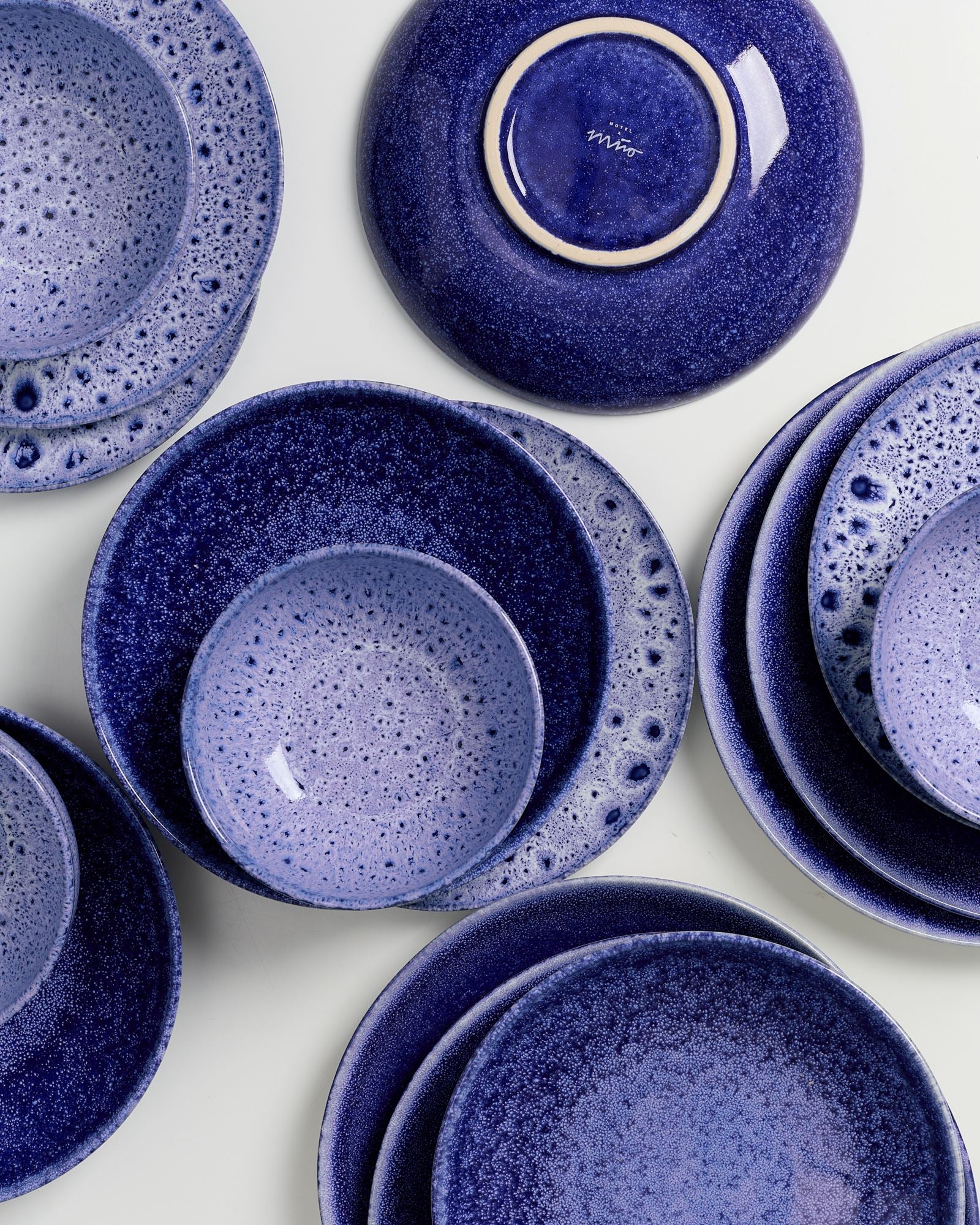 Verschiedene dunkelblaue Keramikteller mit gesprenkeltem Muster auf weißem Hintergrund angeordnet.