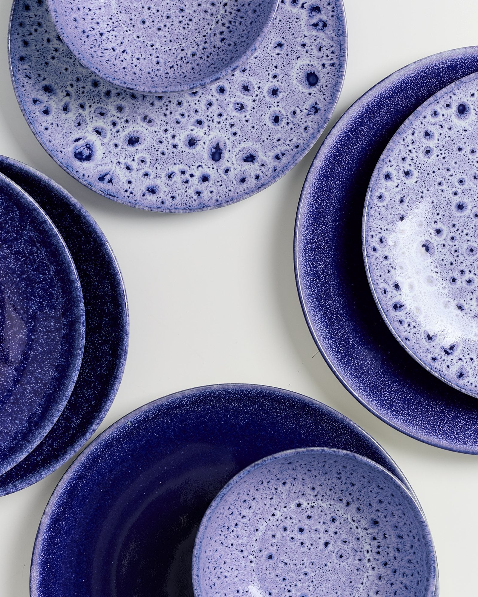 Mehrere blaue und lila gesprenkelte Teller auf einem weißen Hintergrund angeordnet.