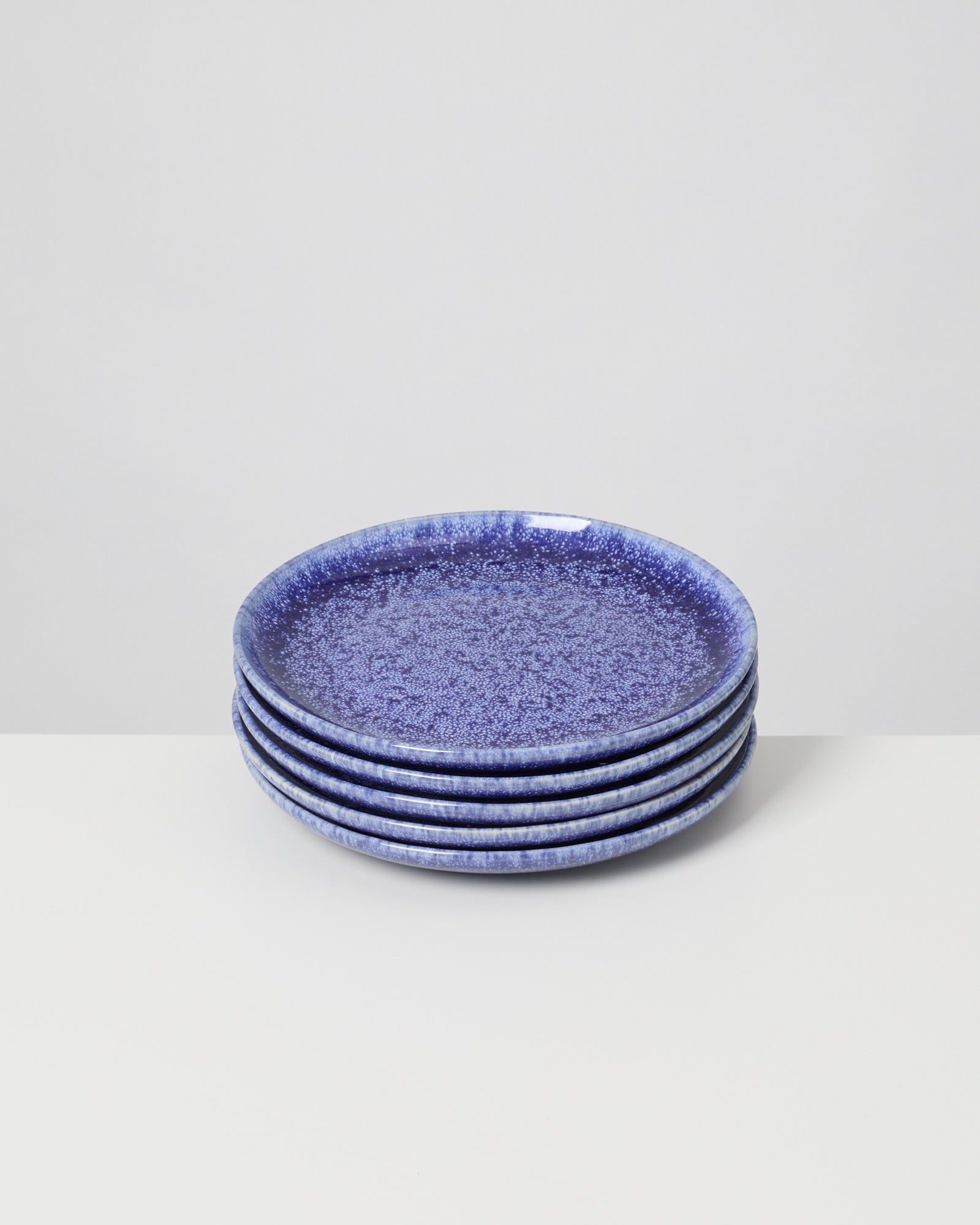 Sechs stapelbare, blau gesprenkelte Teller auf einem weißen Untergrund.
