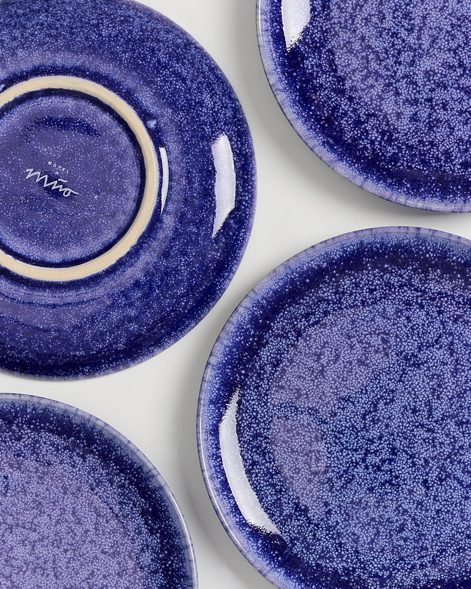 Vier blaue Keramikteller mit gesprenkeltem Muster auf einer hellen Oberfläche.