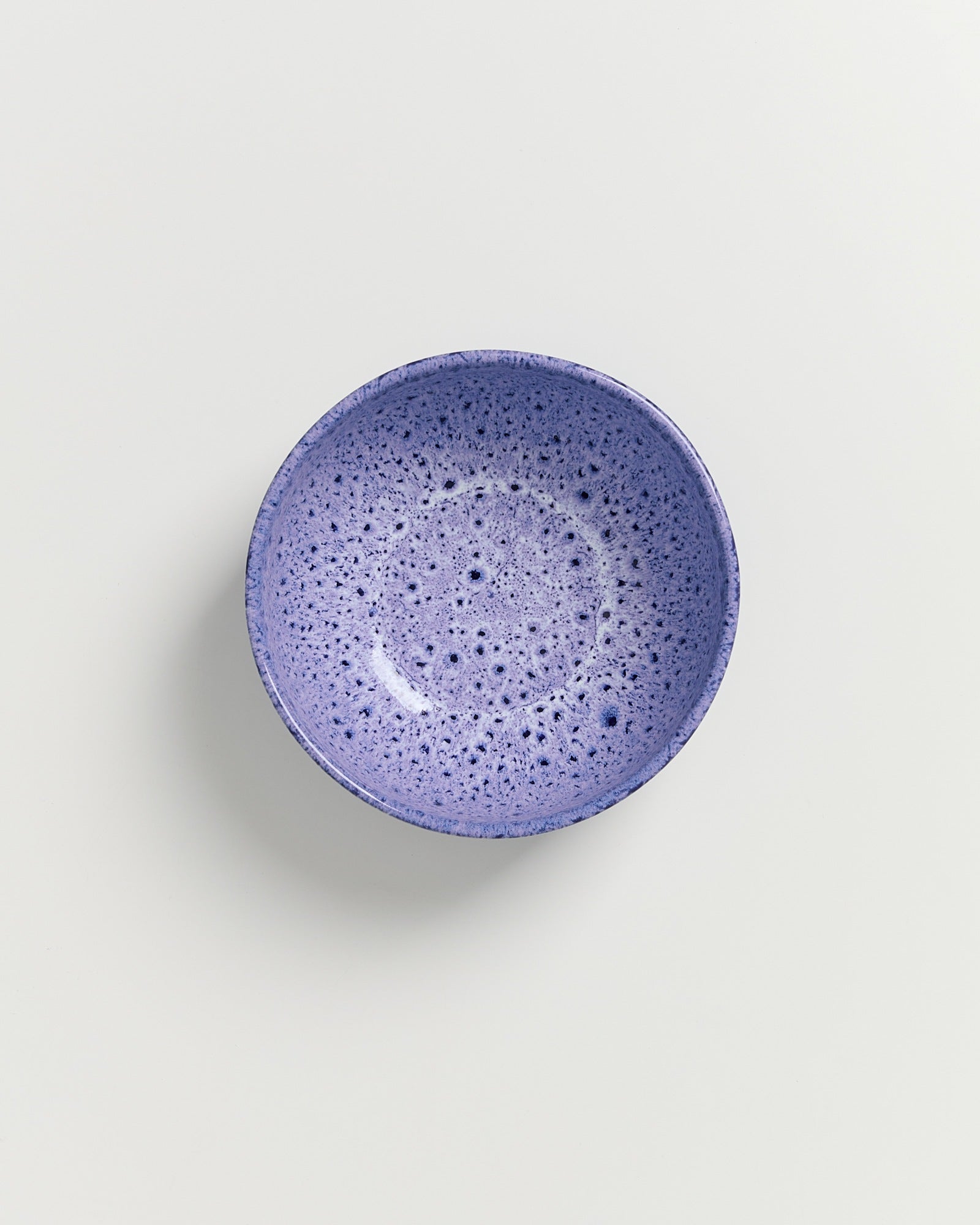 Lila Schale mit gesprenkelter Oberfläche auf weißem Hintergrund.