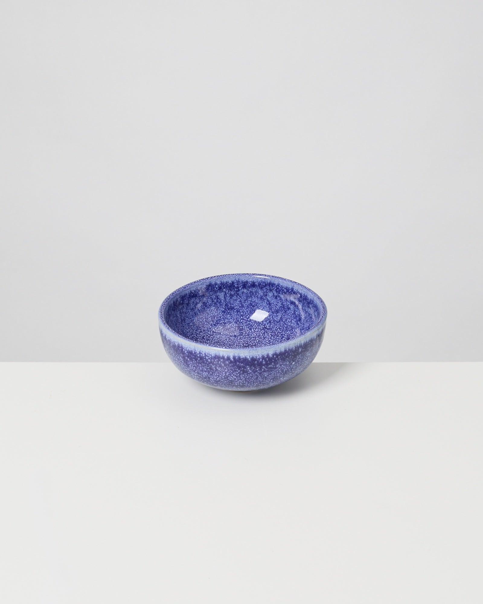 Blaue, keramikartige Schale mit gesprenkeltem Muster auf weißem Hintergrund.