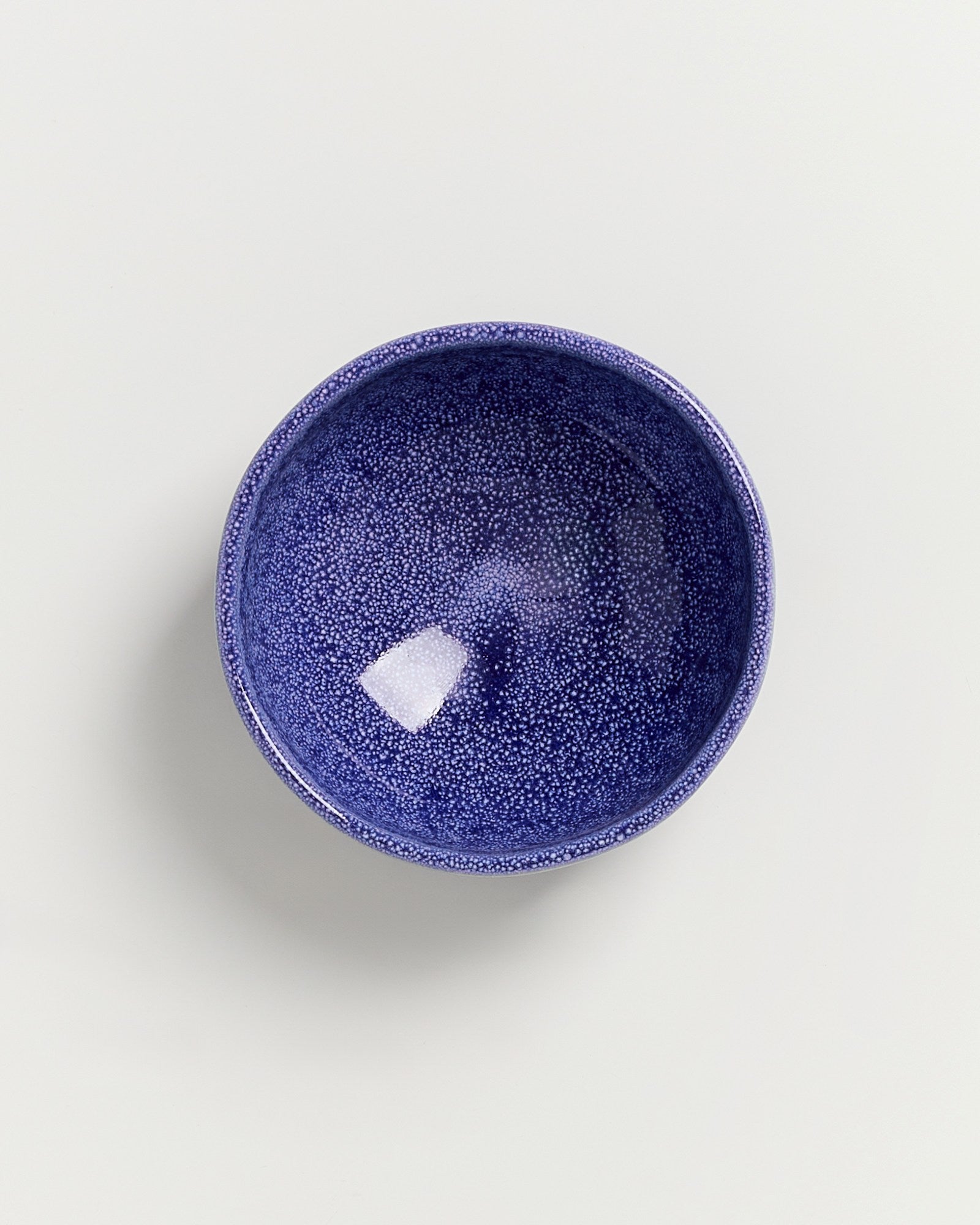 Blau gesprenkelte Schale auf weißem Hintergrund.