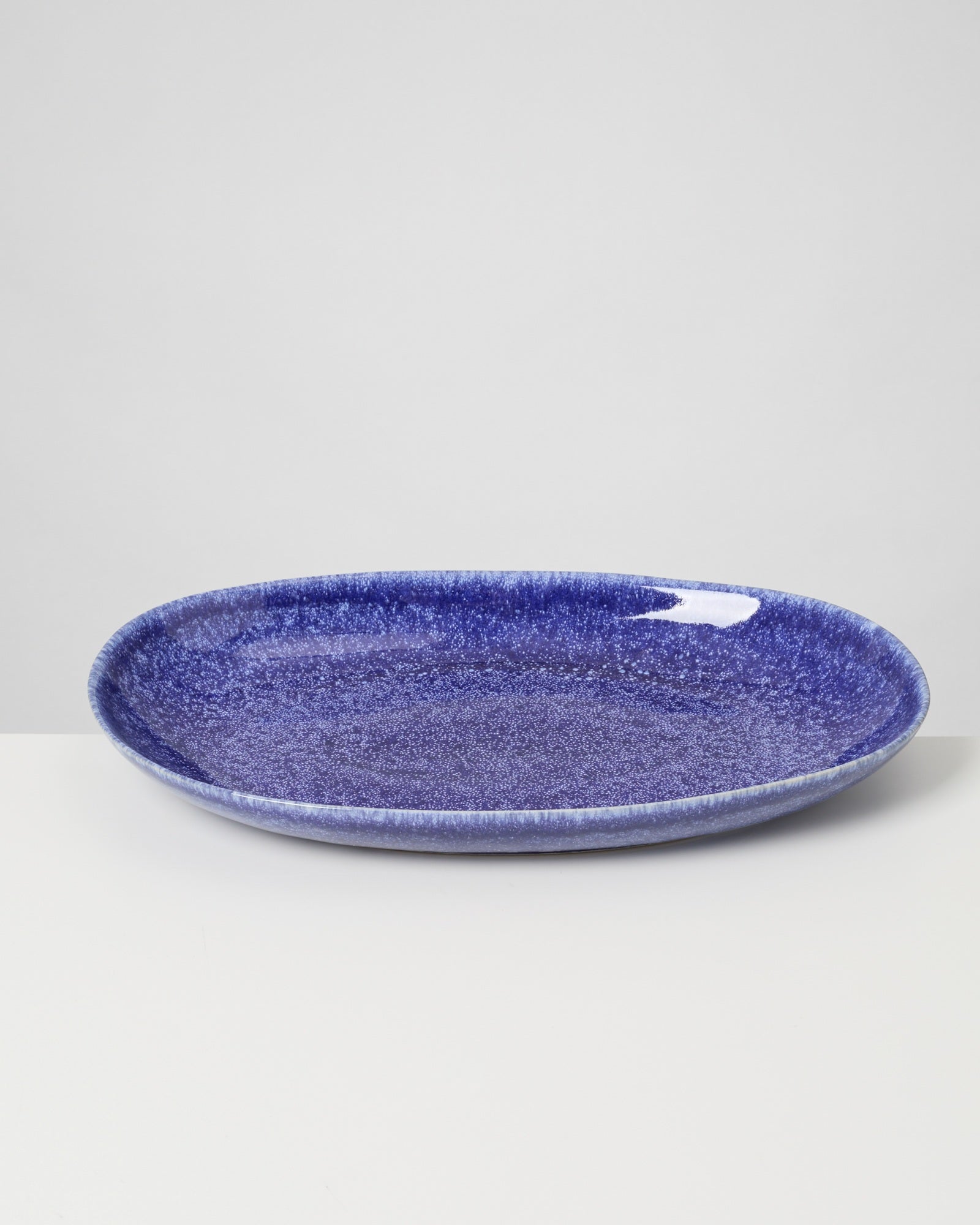 Blauer, ovaler Keramikteller auf weißem Hintergrund.