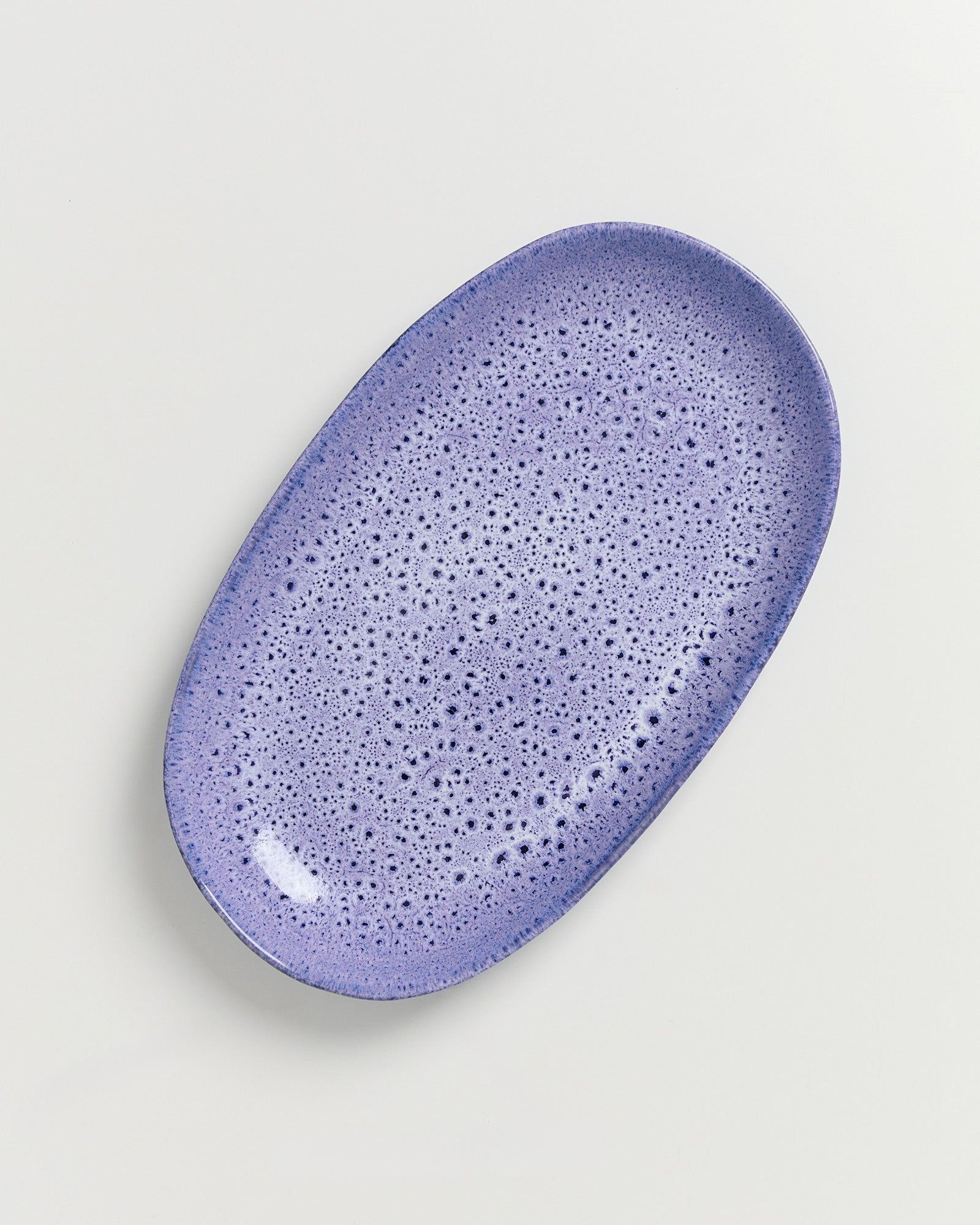 Lila, ovale Keramikplatte mit gesprenkeltem Muster auf weißem Hintergrund.
