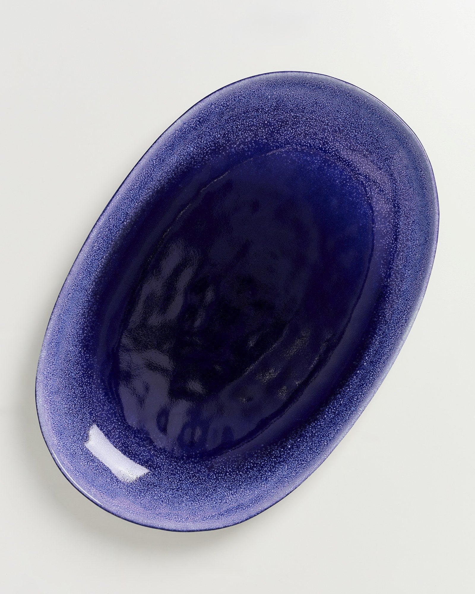 Dunkelblaues, ovales Keramiktablett auf einem weißen Hintergrund.