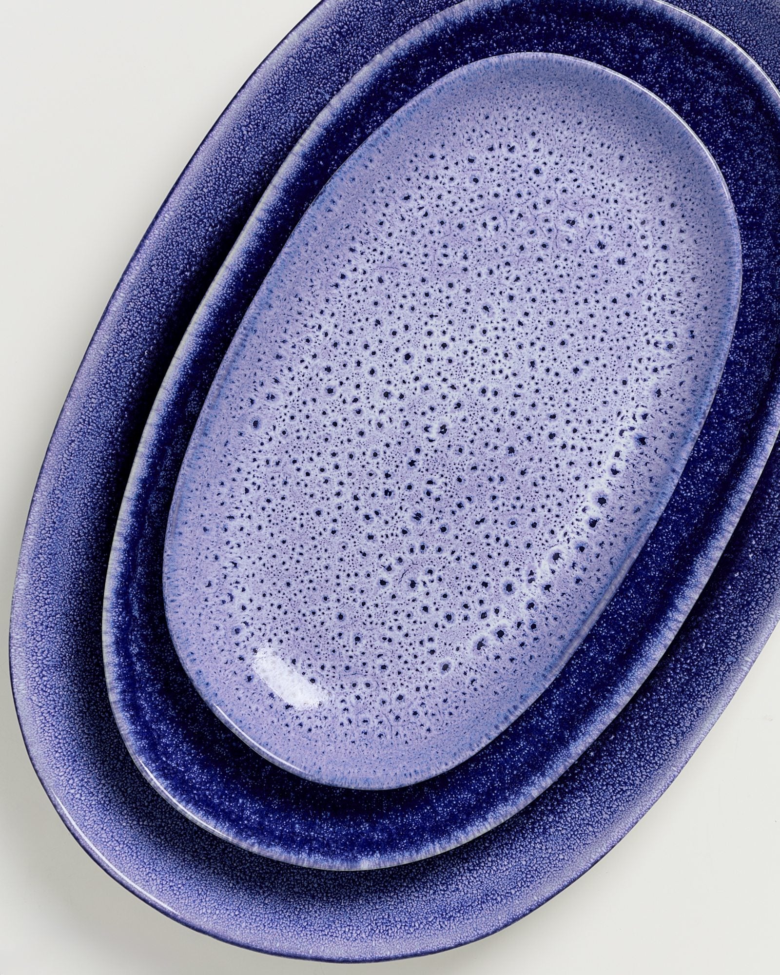 Drei ineinander liegende ovale, blaue Teller auf weißem Hintergrund.