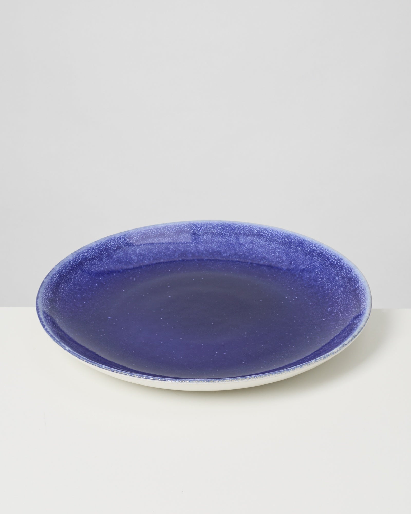 Blauer Keramikteller auf weißem Hintergrund.