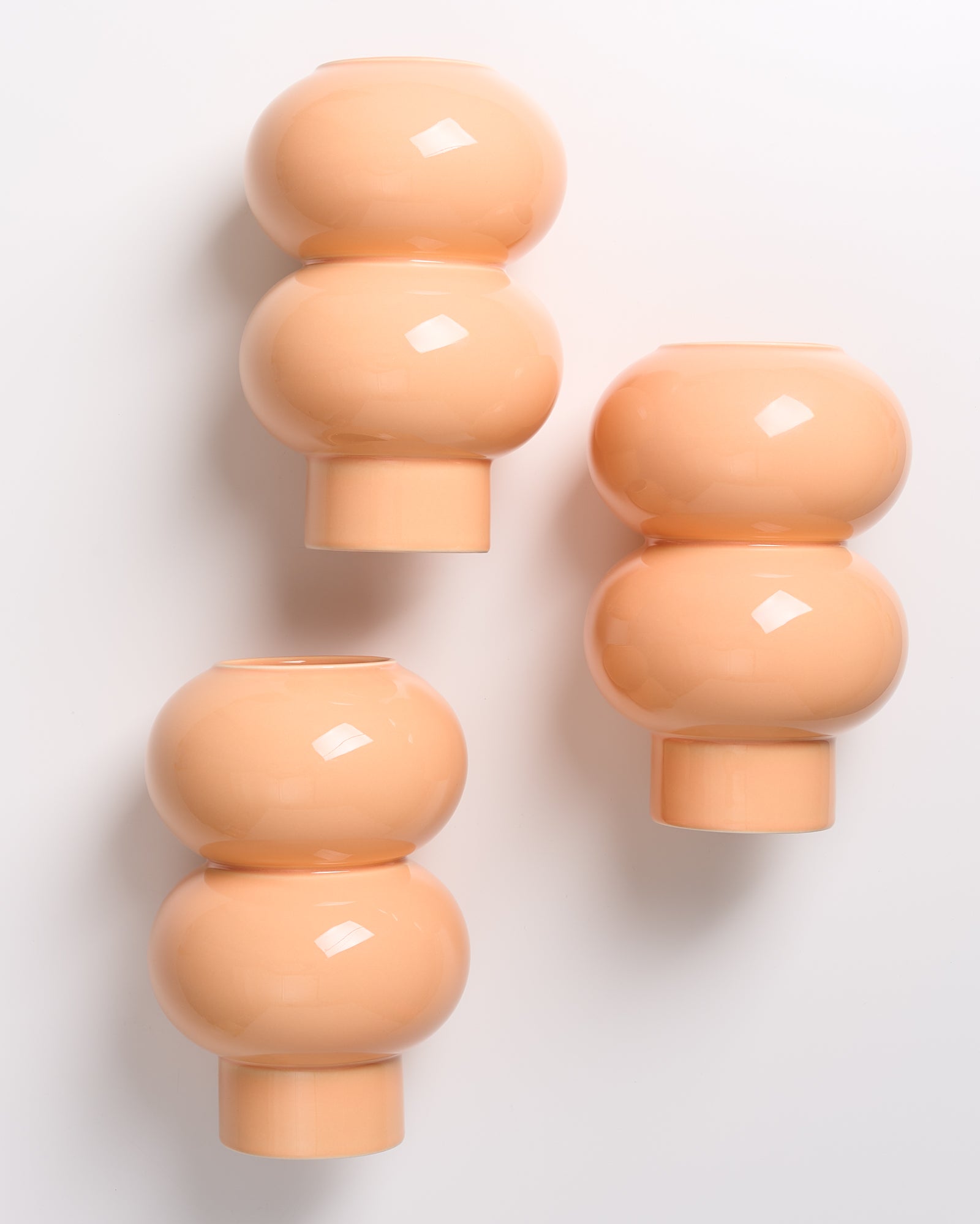 Drei beigefarbene, kugelförmige Vasen stehen auf einem weißen Hintergrund.