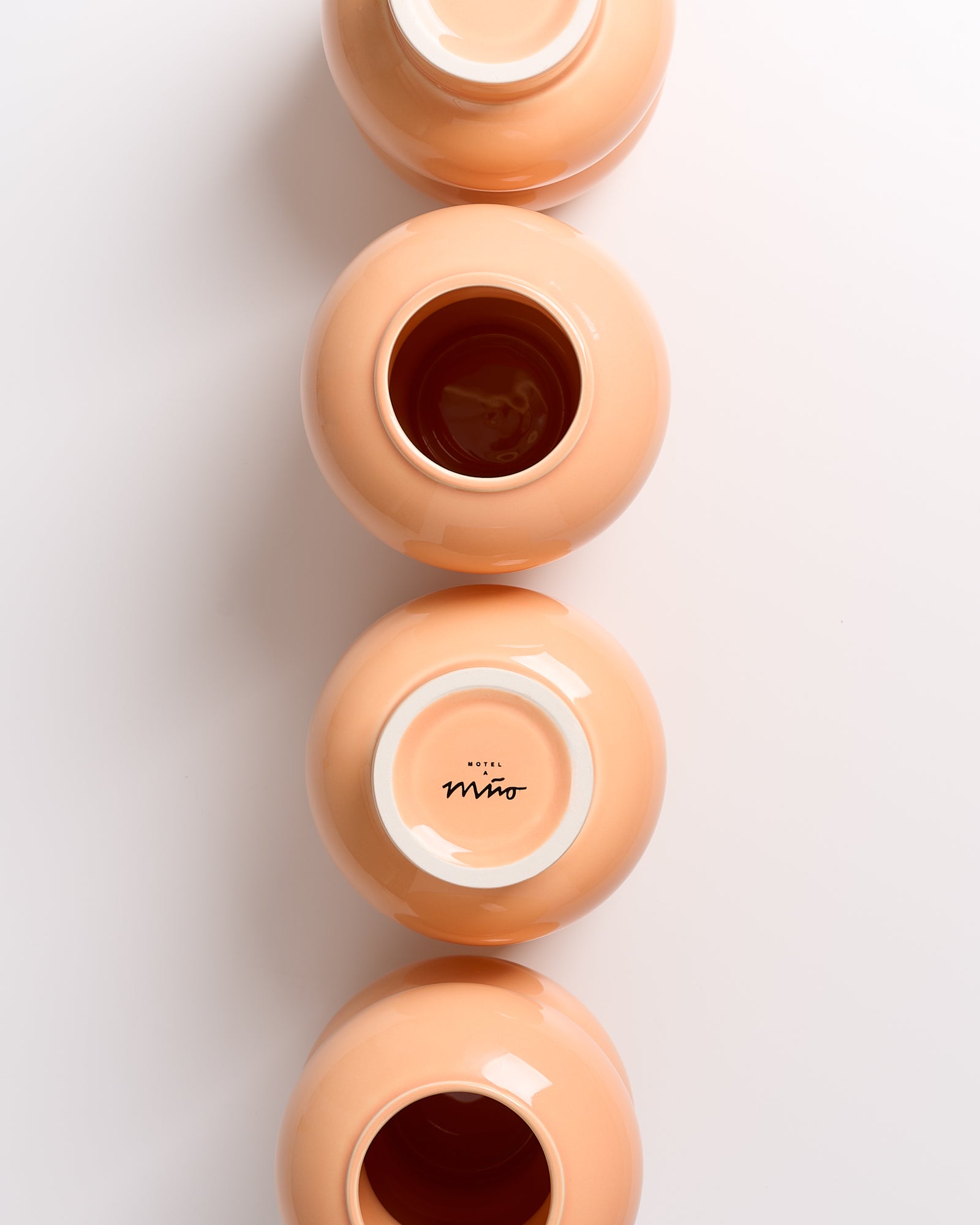 Vier orangefarbene Schalen von oben, zwei mit Öffnungen nach oben, zwei mit dem Boden nach oben, zeigen "Hotel Miro".