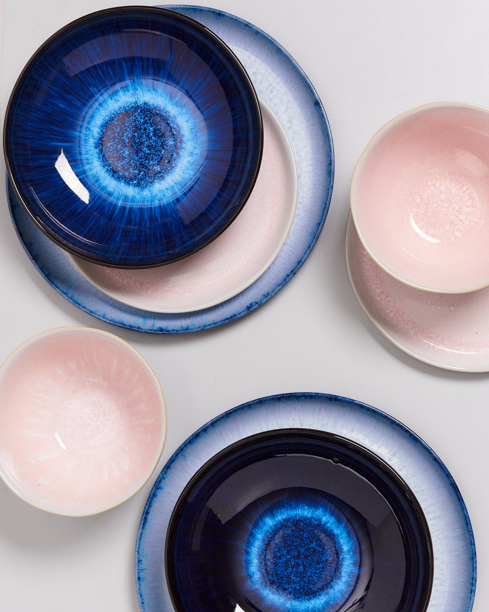 Blau- und rosafarbene Teller und Schalen mit kunstvollen Mustern auf einem hellen Hintergrund.