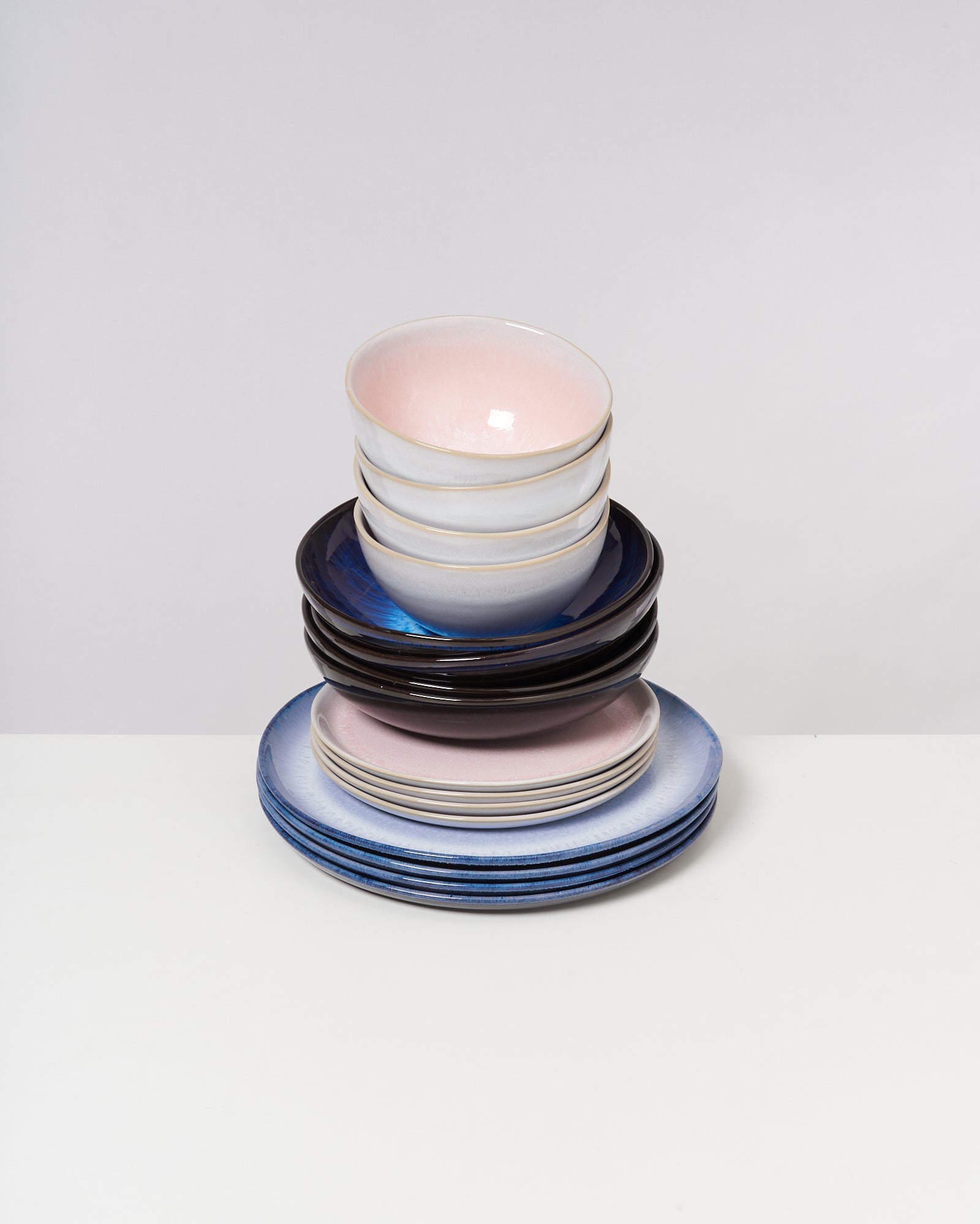 Ein Stapel von Schalen und Tellern in verschiedenen Farben und Größen auf einem weißen Hintergrund.