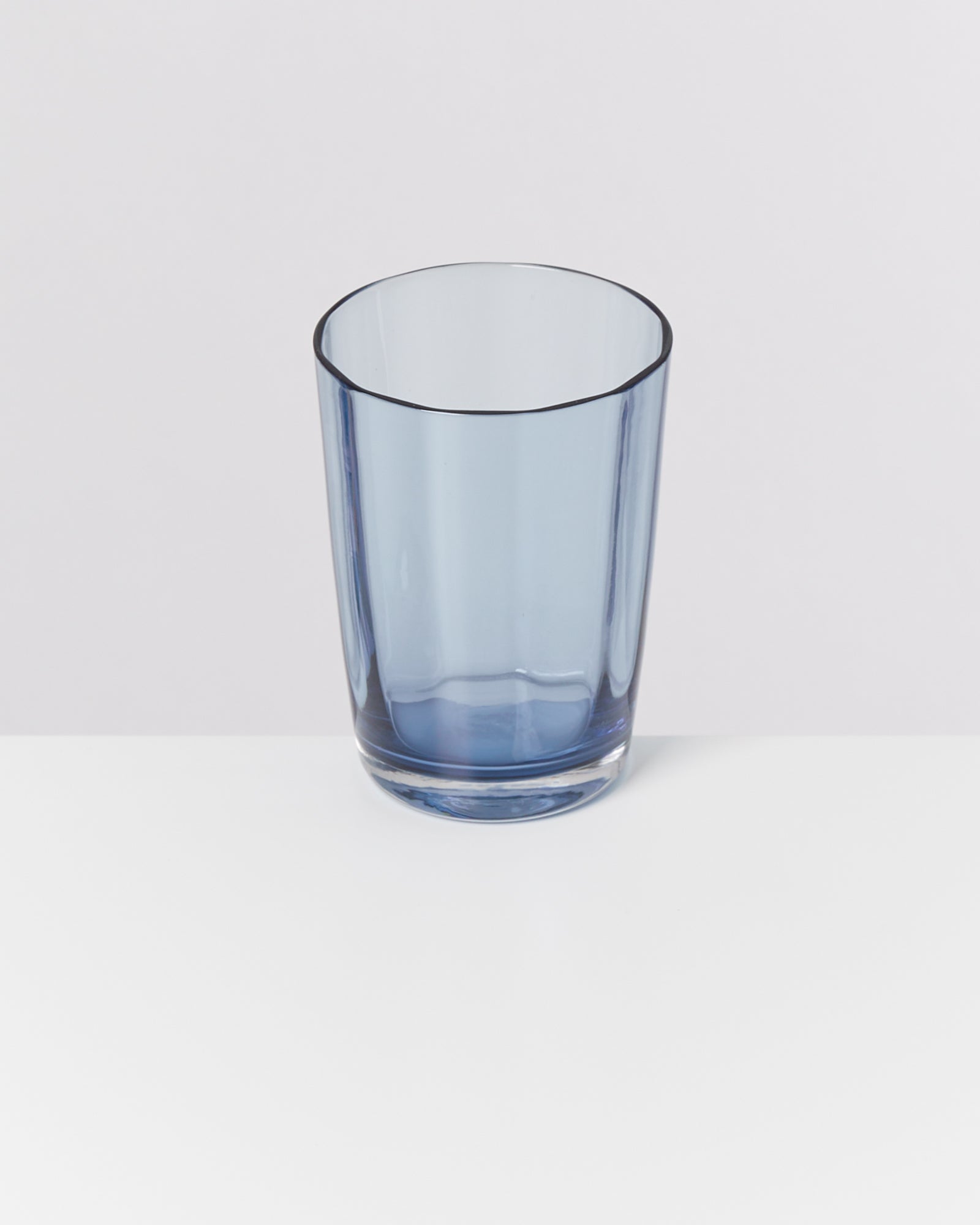 Blaues Trinkglas auf weißem Hintergrund, in der unteren rechten Ecke positioniert.