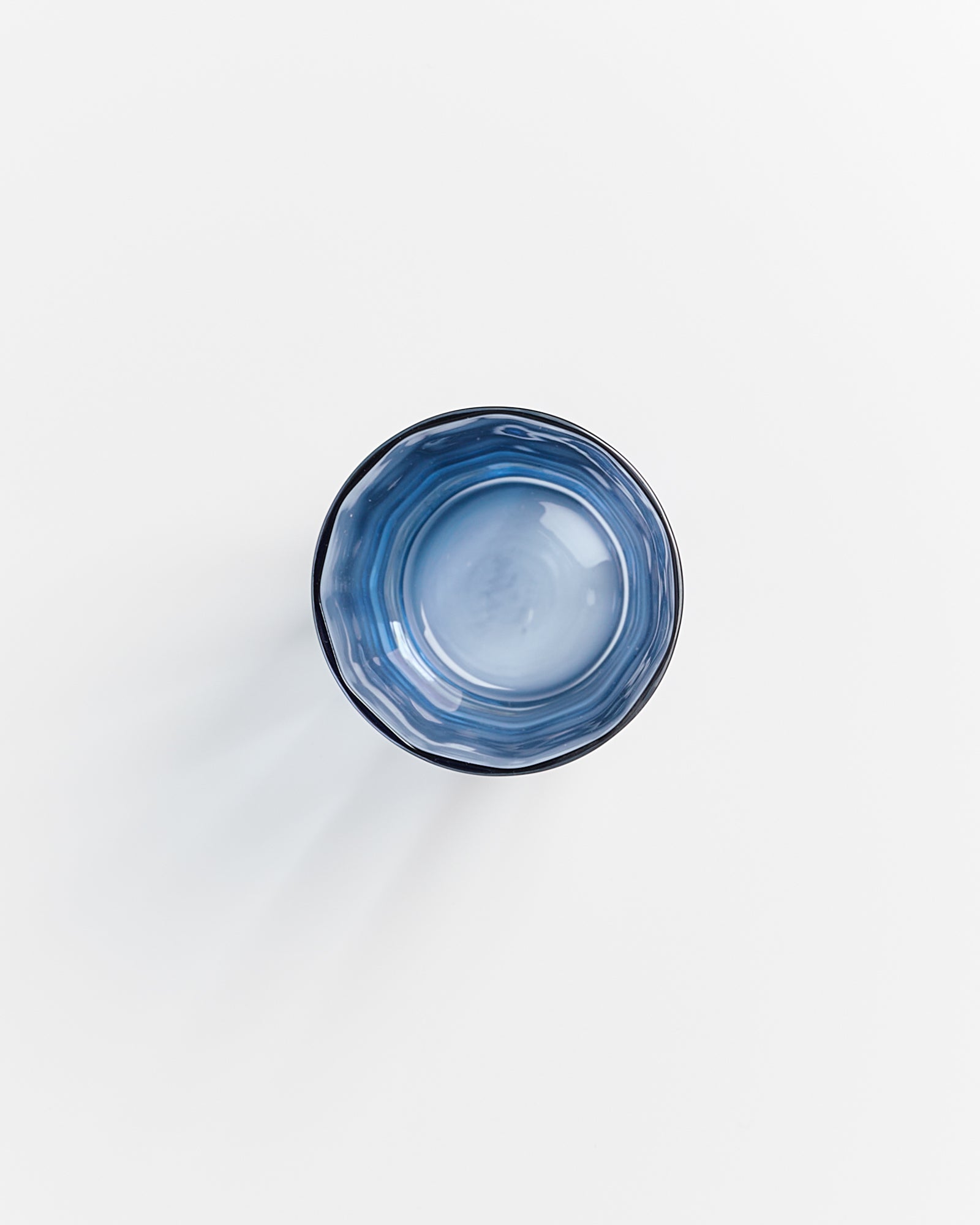 Blaues Trinkglas von oben fotografiert auf weißem Hintergrund.