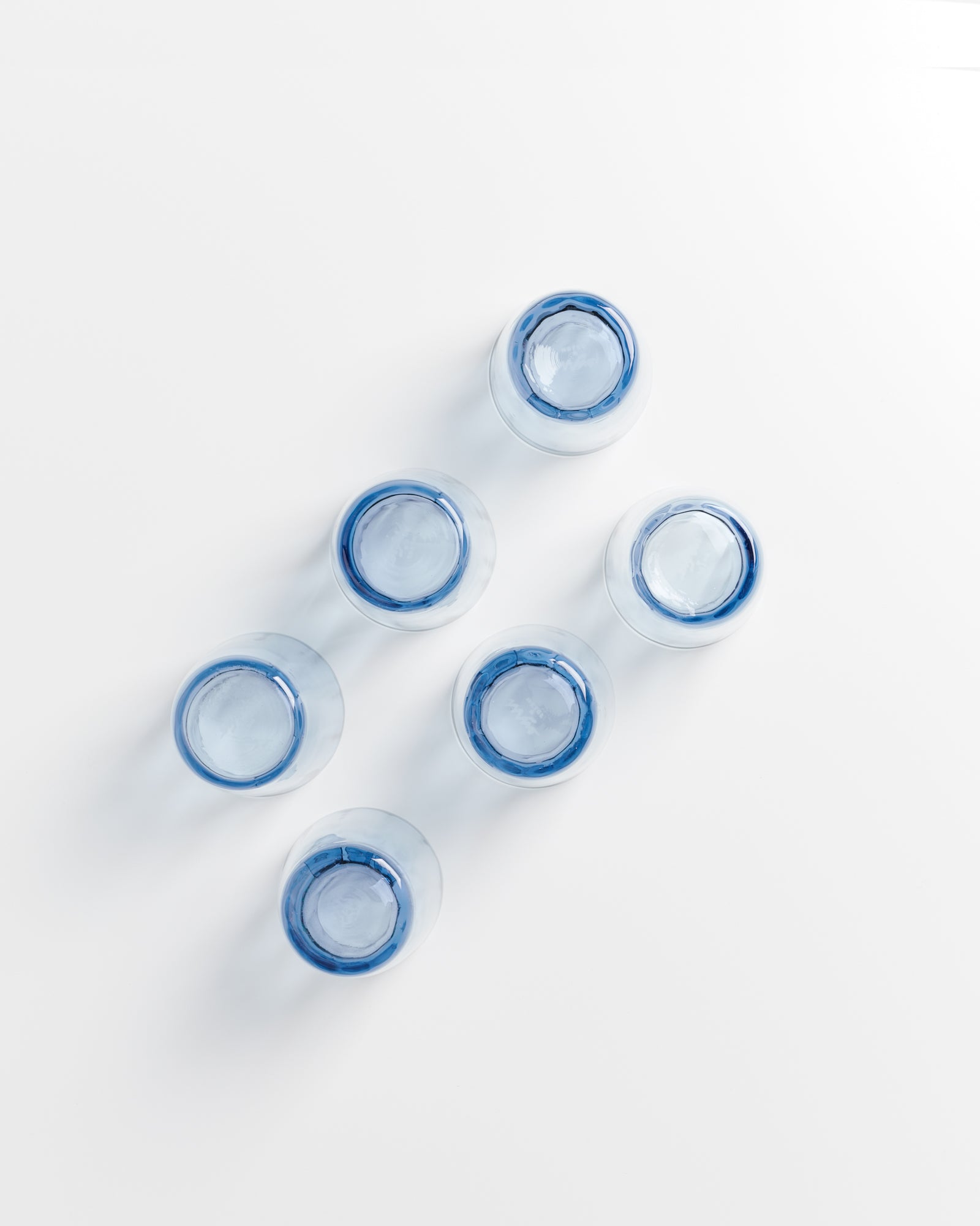 Sechs blaue Gläser, von oben gesehen, auf einem weißen Hintergrund angeordnet.