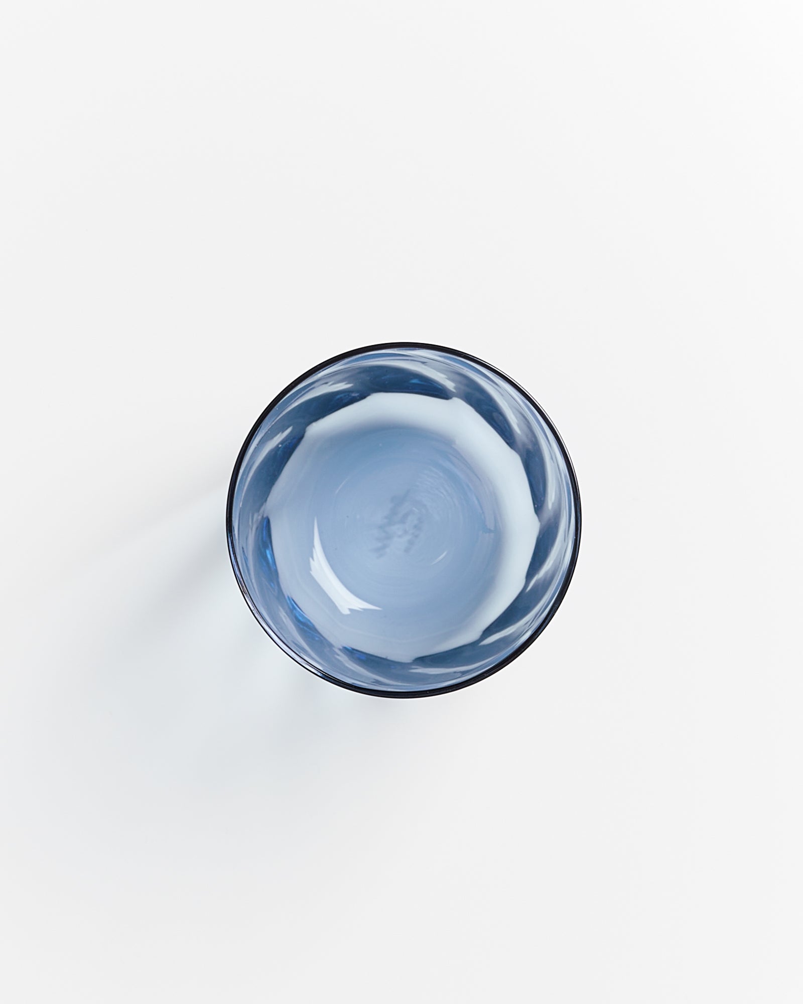 Blaue Glasschale auf weißem Hintergrund von oben fotografiert.