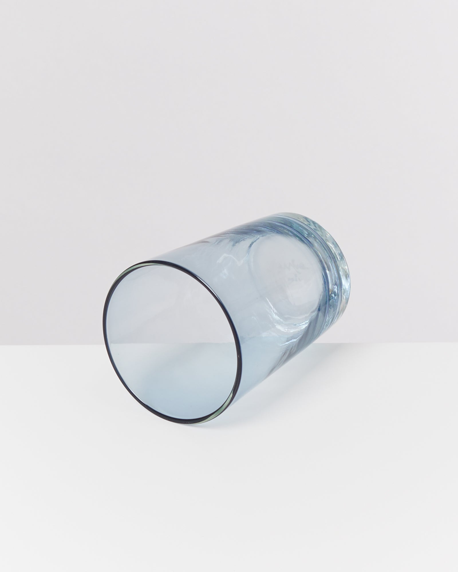 Blaues Glas liegt auf der Seite auf einem weißen Hintergrund.