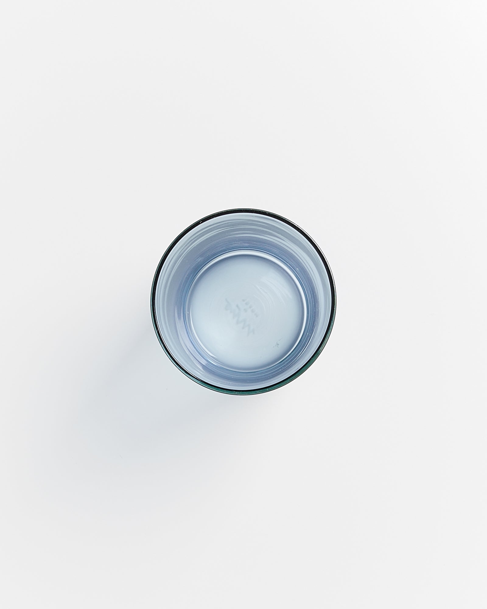 Ein Glas mit Wasser aus der Vogelperspektive auf weißem Hintergrund.