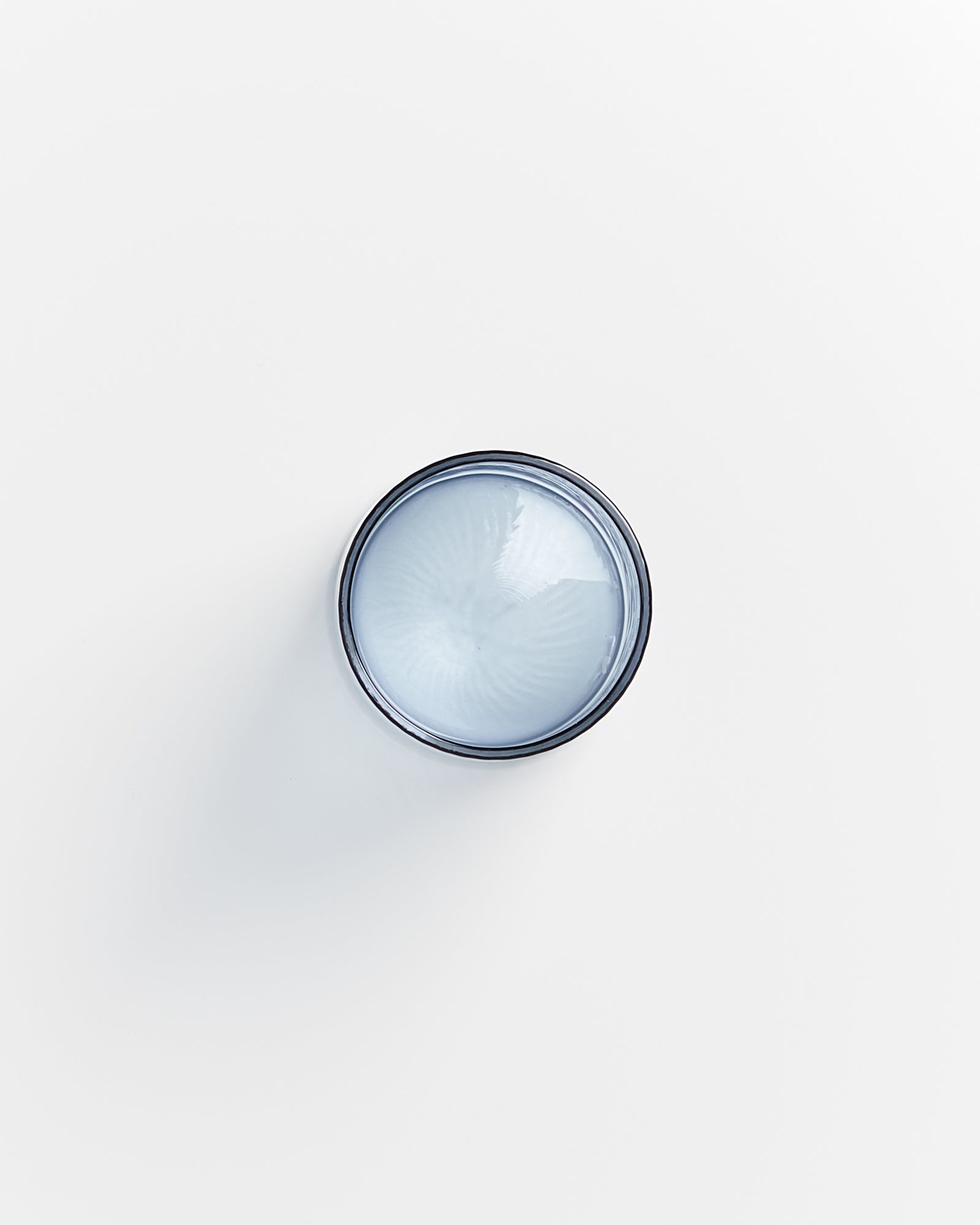 Rundbehälter mit blauem Inhalt auf weißem Hintergrund von oben fotografiert.