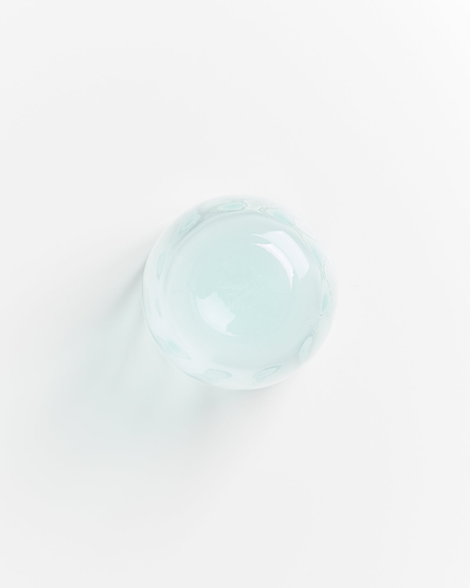 Glaskugel auf weißem Hintergrund, von oben fotografiert.
