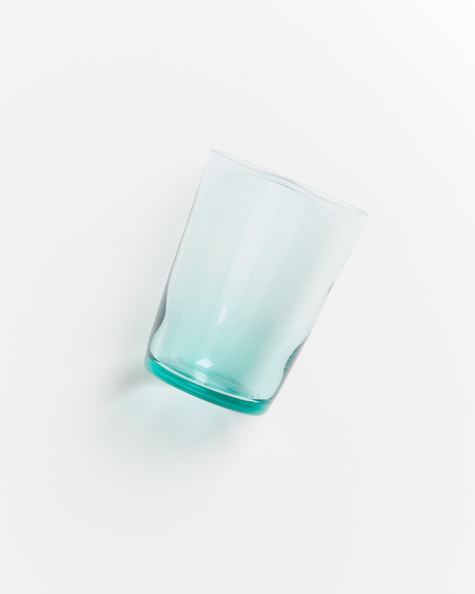 Ein leicht schräg liegendes, halb voll transparentes Glas auf weißem Hintergrund.