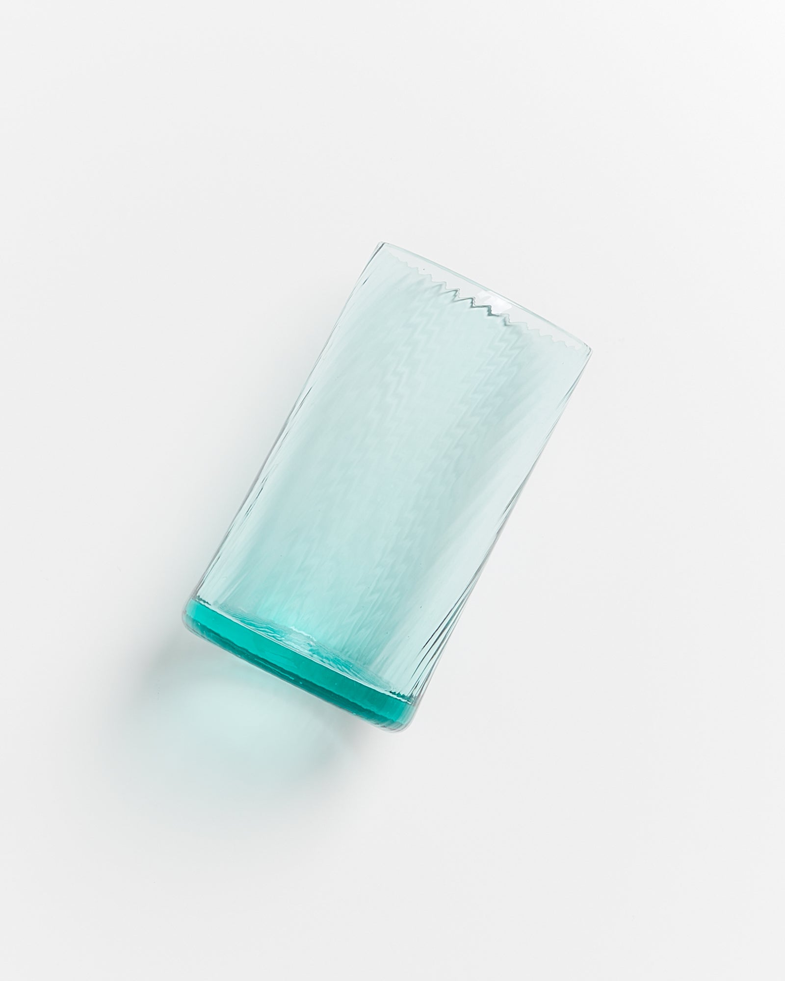 Ein umgekippter, leerer, blauer Trinkbecher liegt auf einer weißen Oberfläche.