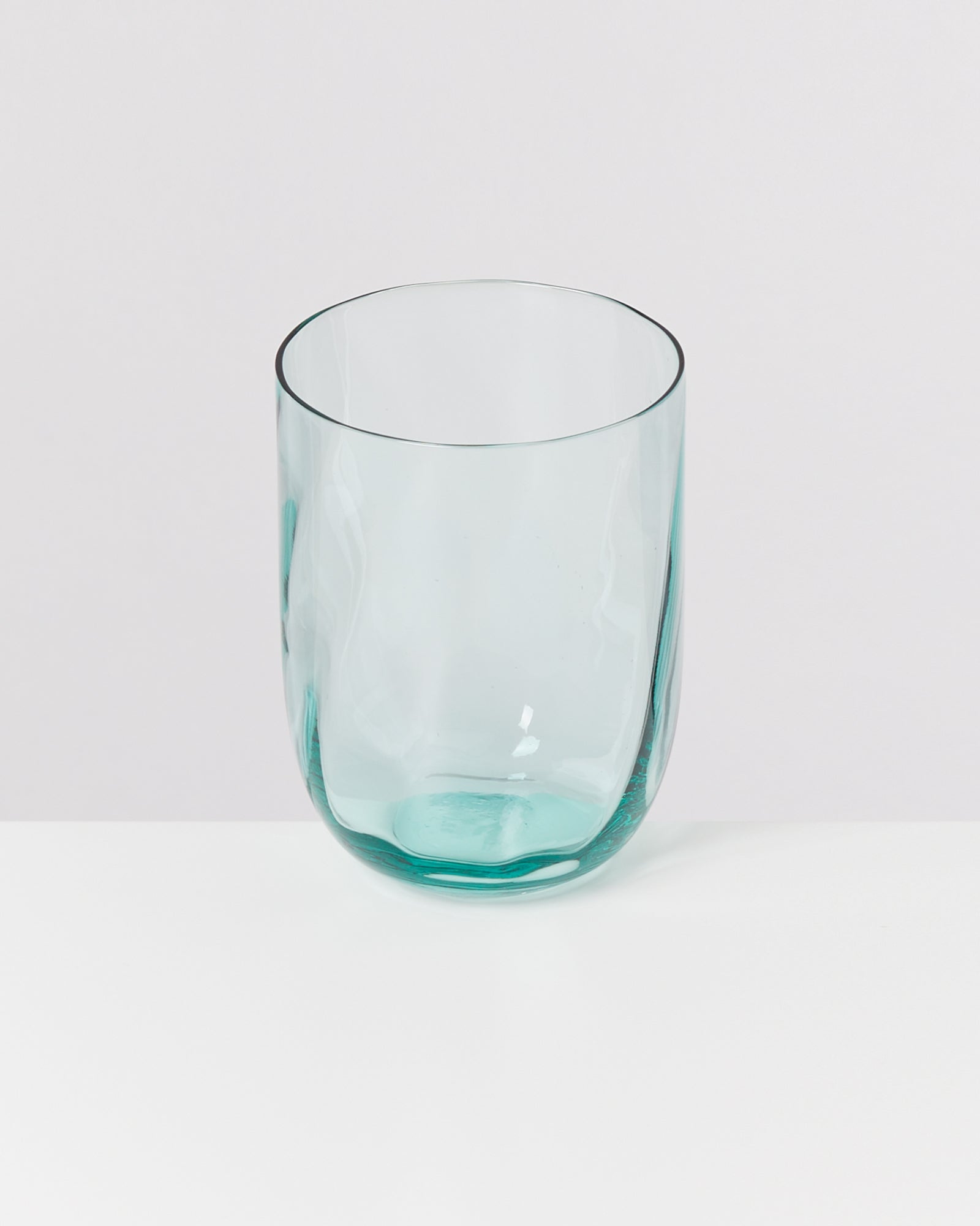 Ein durchsichtiges, bläuliches Glas steht auf einer weißen Oberfläche.