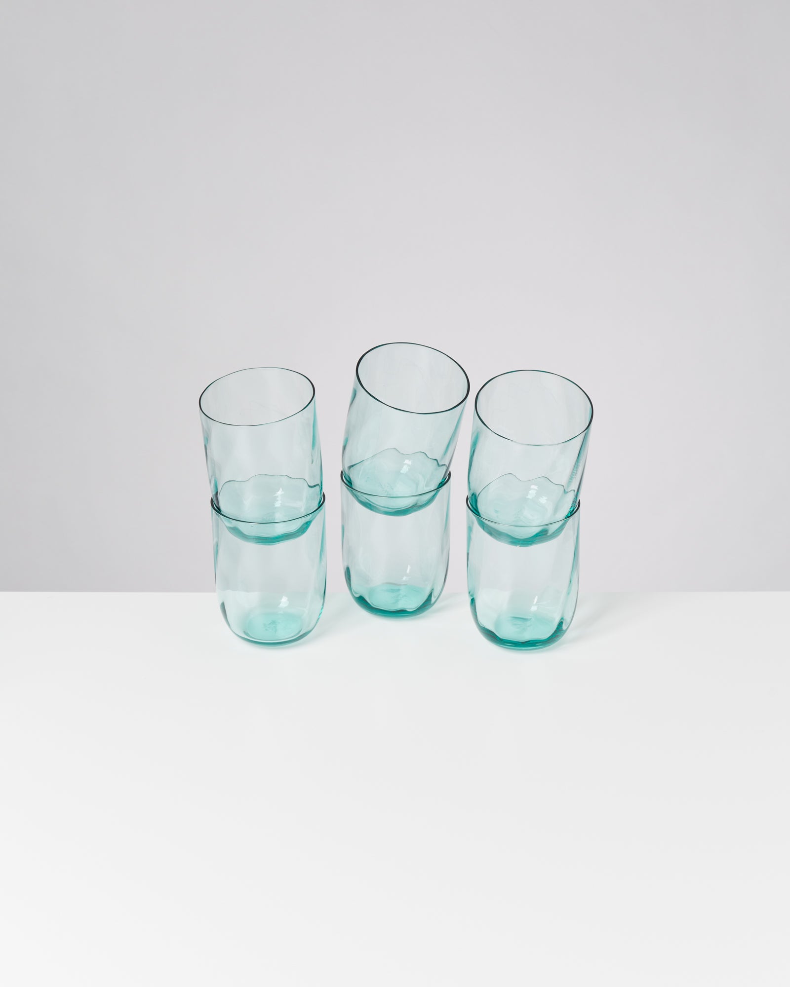 Drei überlappende grüne Gläser stehen auf einer weißen Oberfläche.