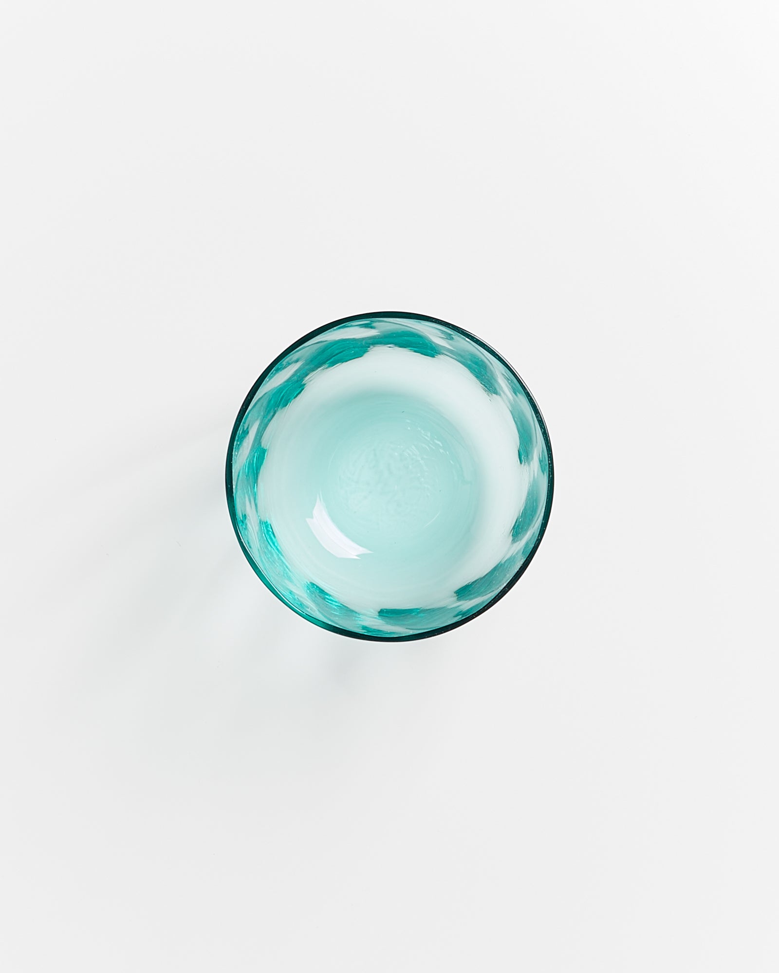 Türkis-weiße Glasschale von oben fotografiert auf einem weißen Hintergrund.
