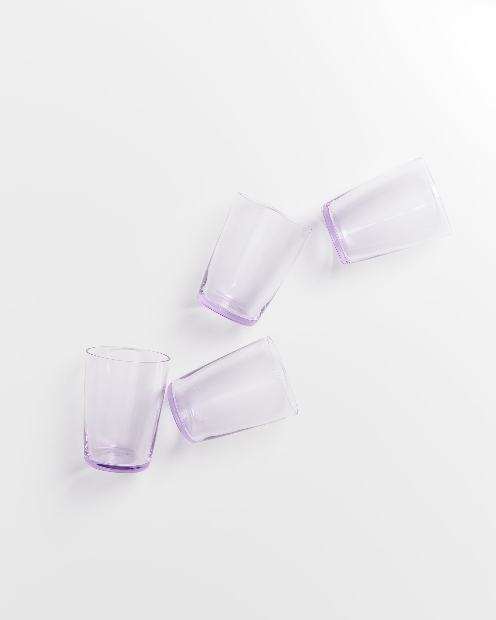 Vier lila Gläser auf einer weißen Oberfläche, schräg angeordnet.