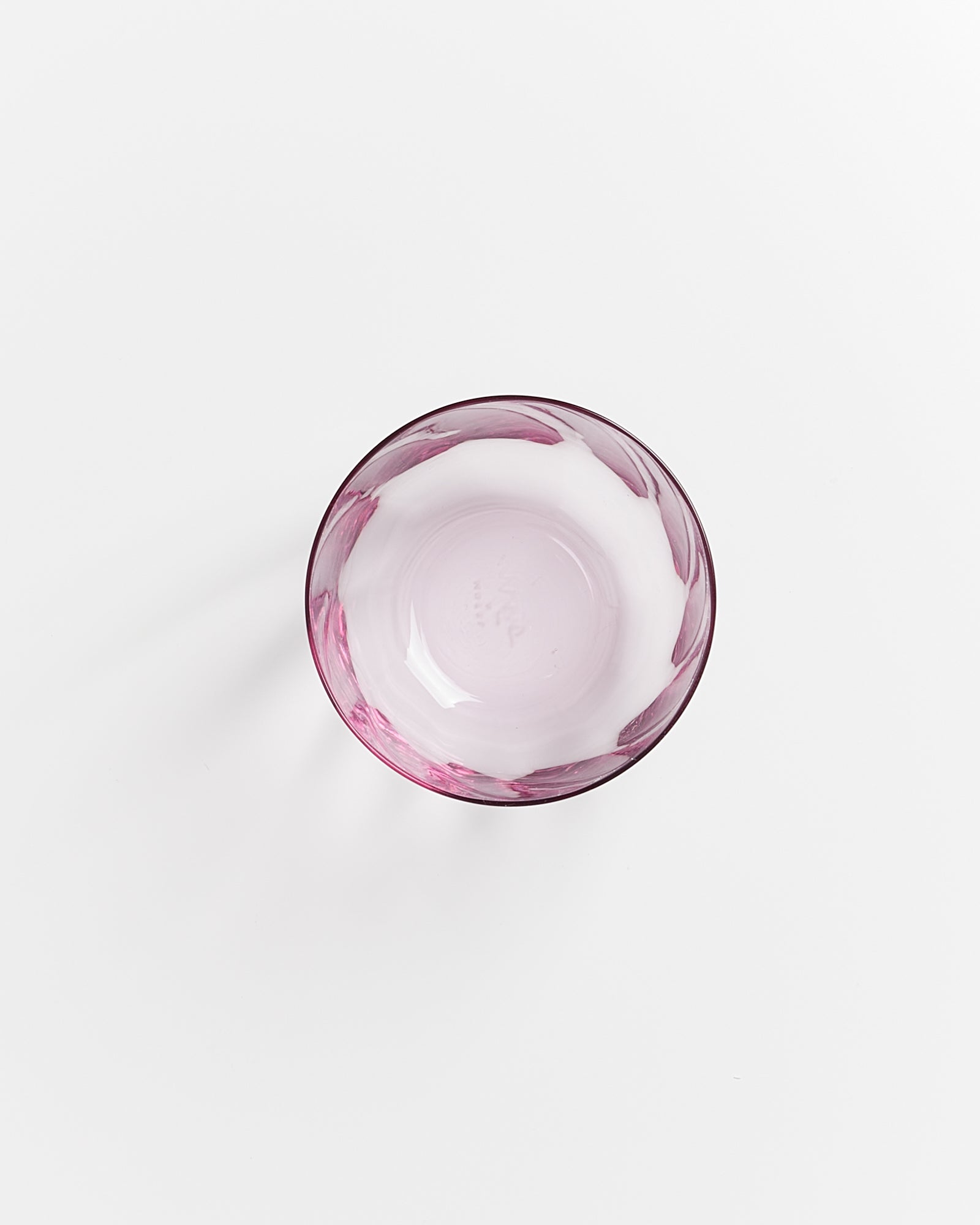 Runde, rosafarbene Glasschüssel von oben auf weißem Hintergrund.