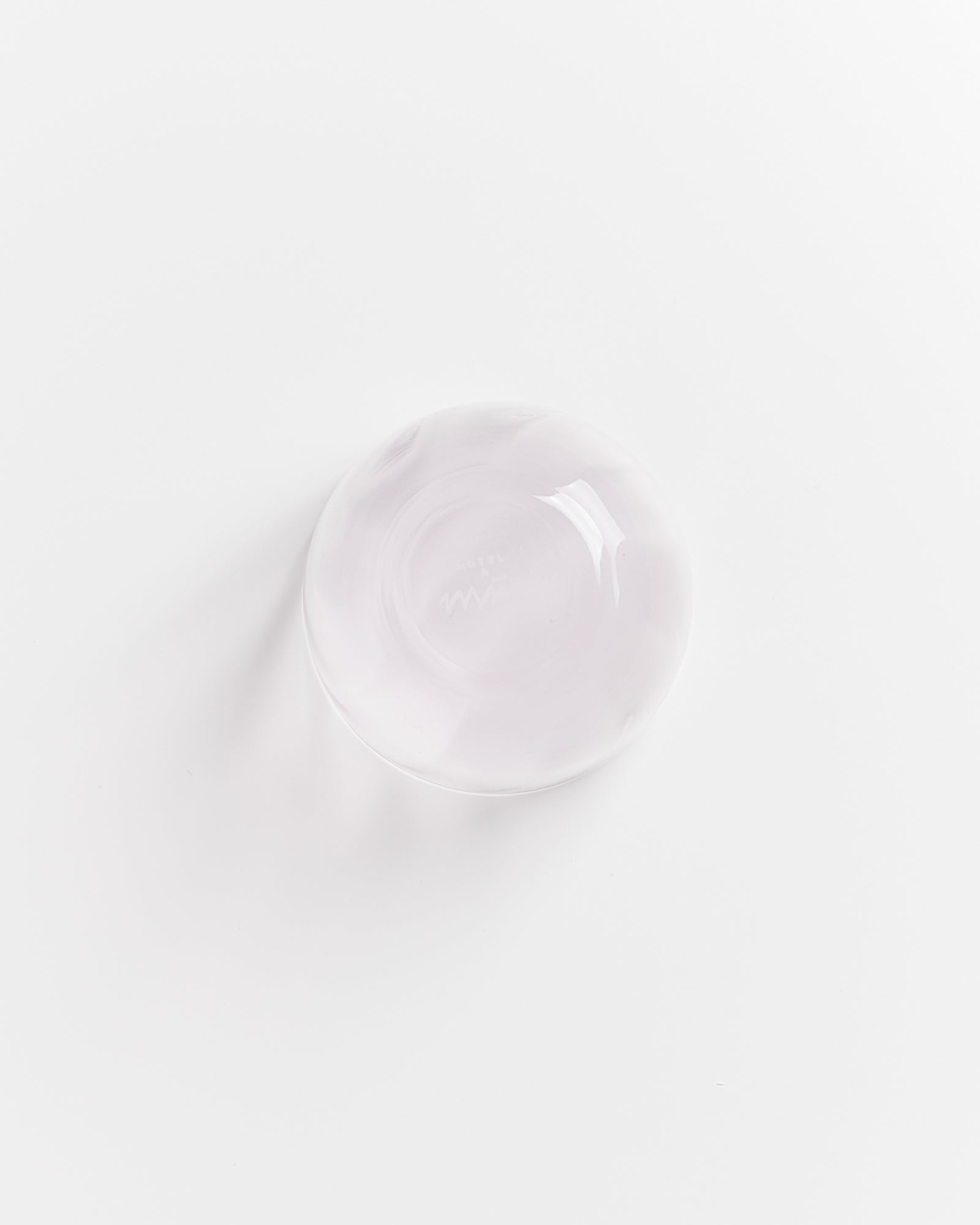 Eine klare Glasschale mit einem leichten Lila-Ton steht auf einer weißen Oberfläche.